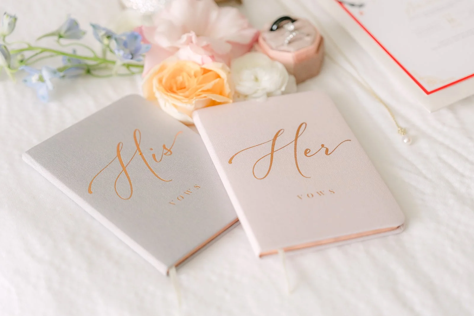 Amanda and San's His and Hers vow books with pastel florals.