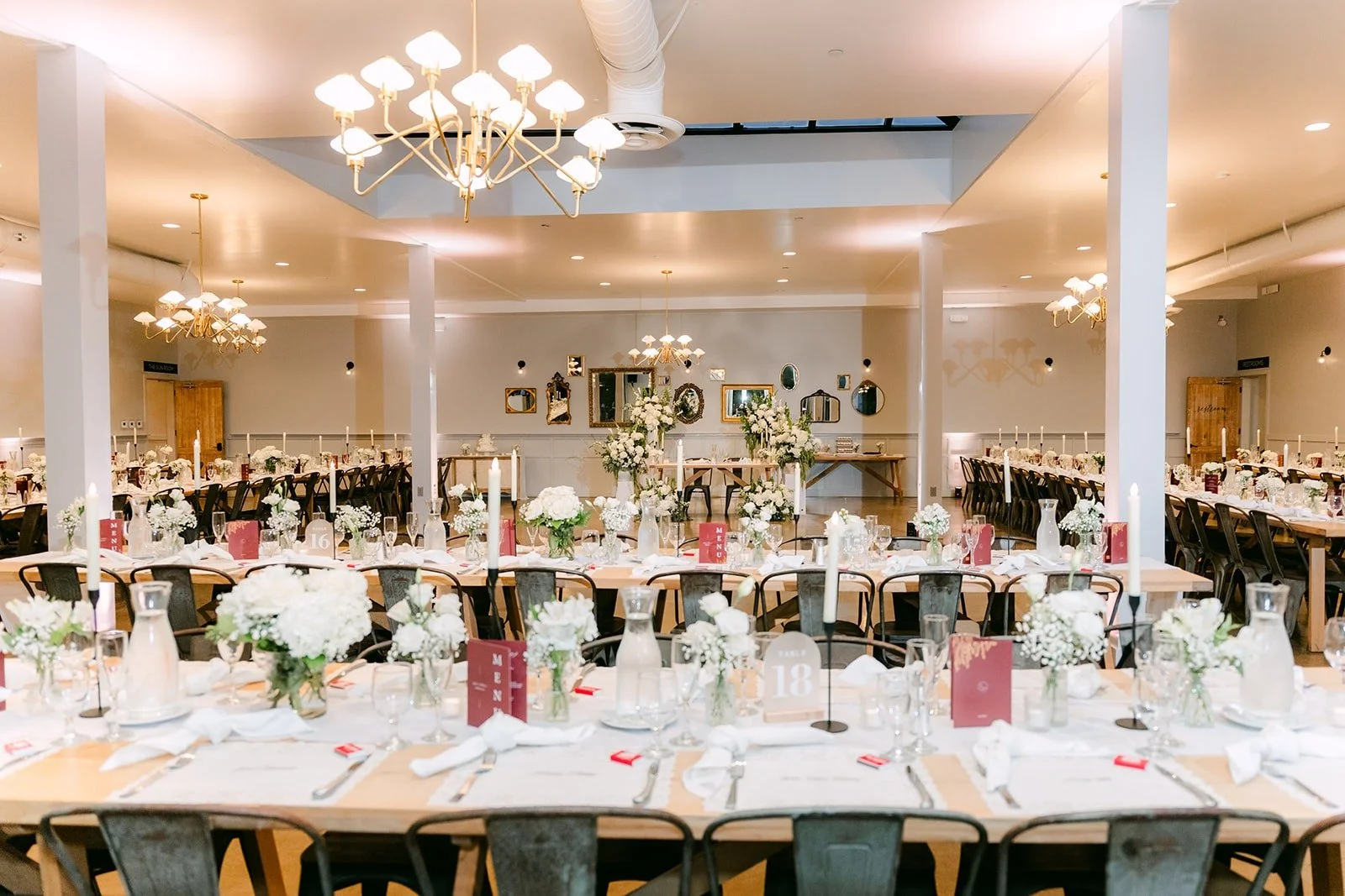 The reception room at The Harper set with long tables, white florals and chandeliers