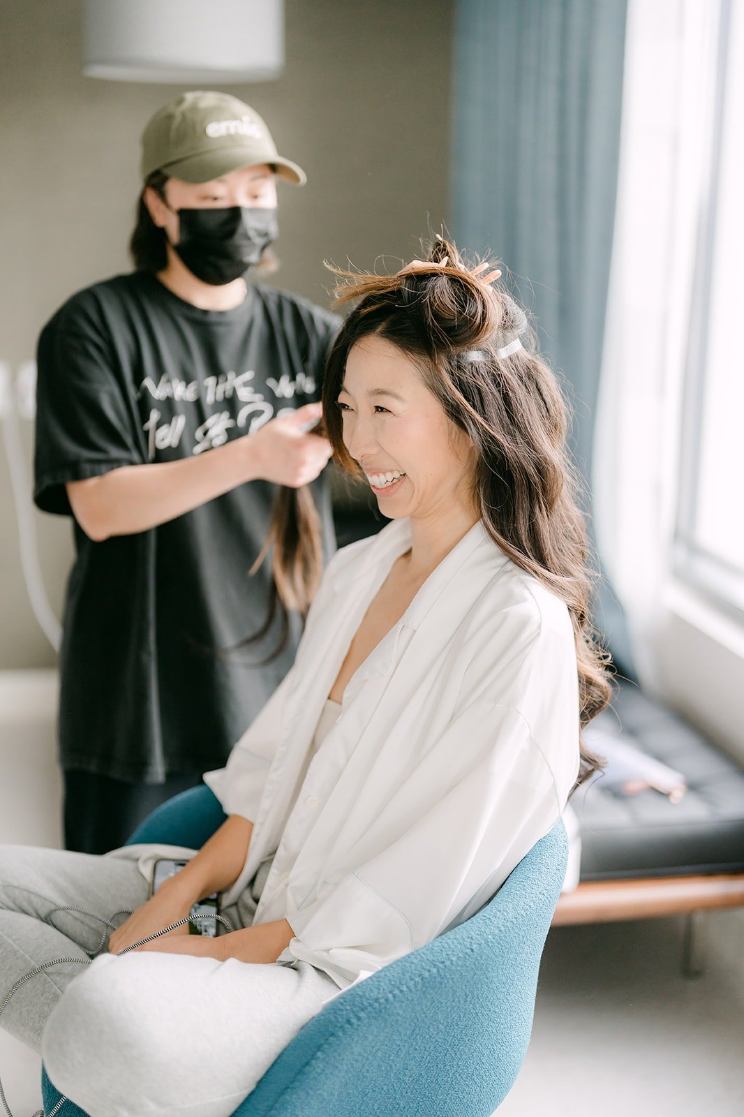 Kristine laughing in a white robe while her hair is styled