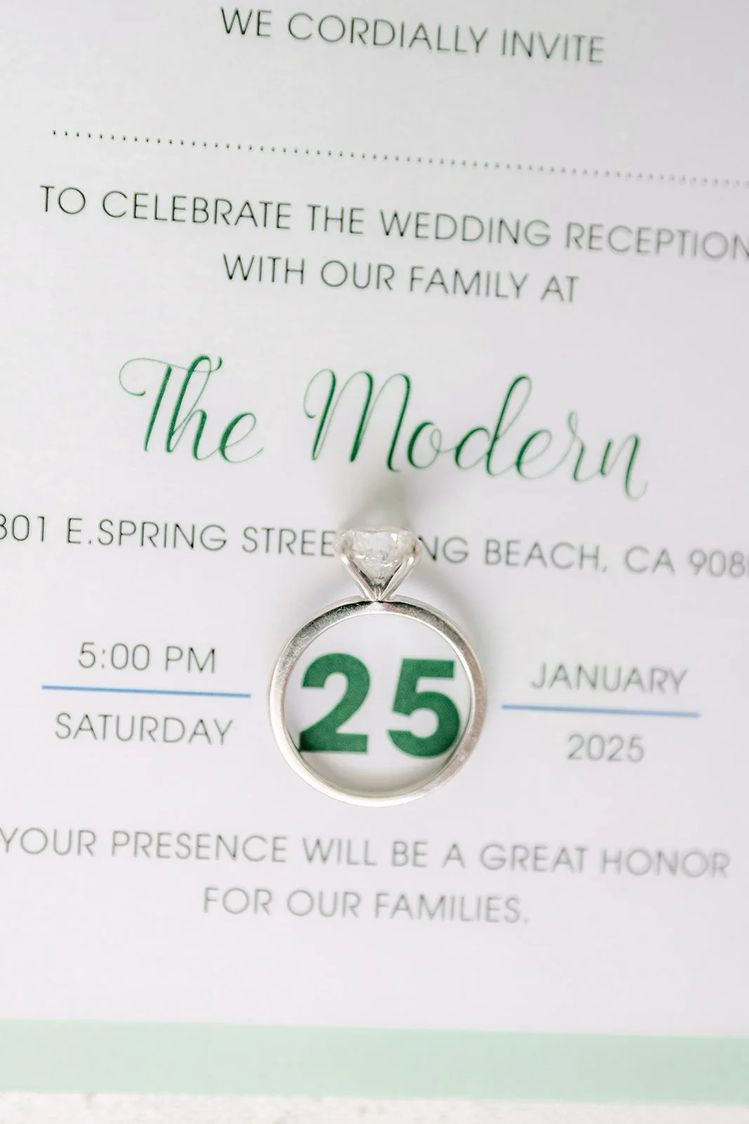 Close up of The Modern Long Beach invitation with an engagement ring framing the date 25