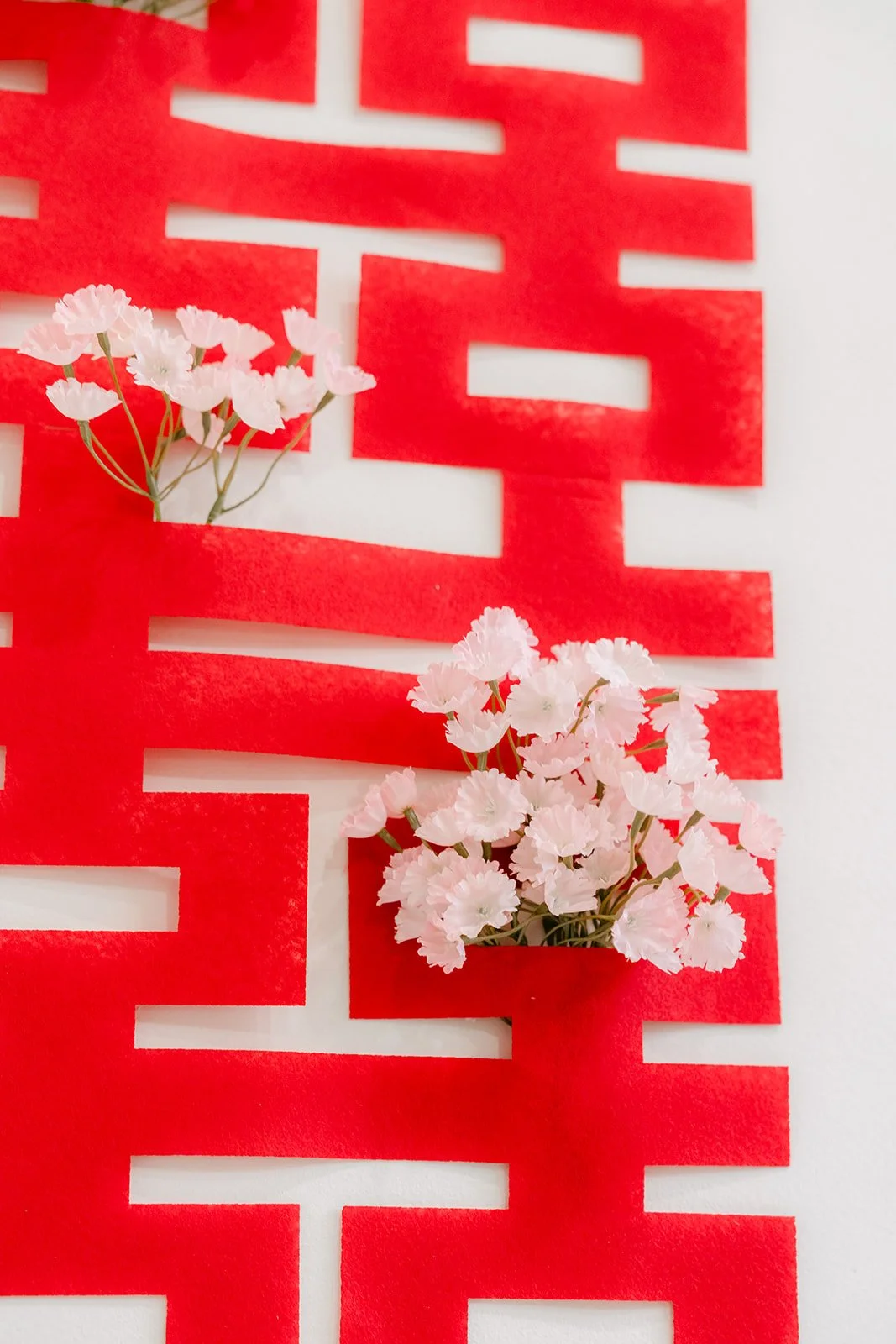 Close up of a red double happiness papercut decorated with pink flowers.