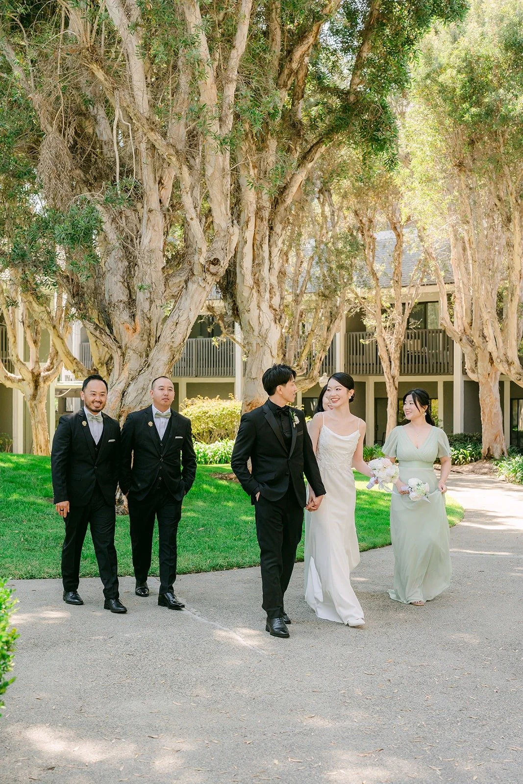 The wedding party walking together under the trees