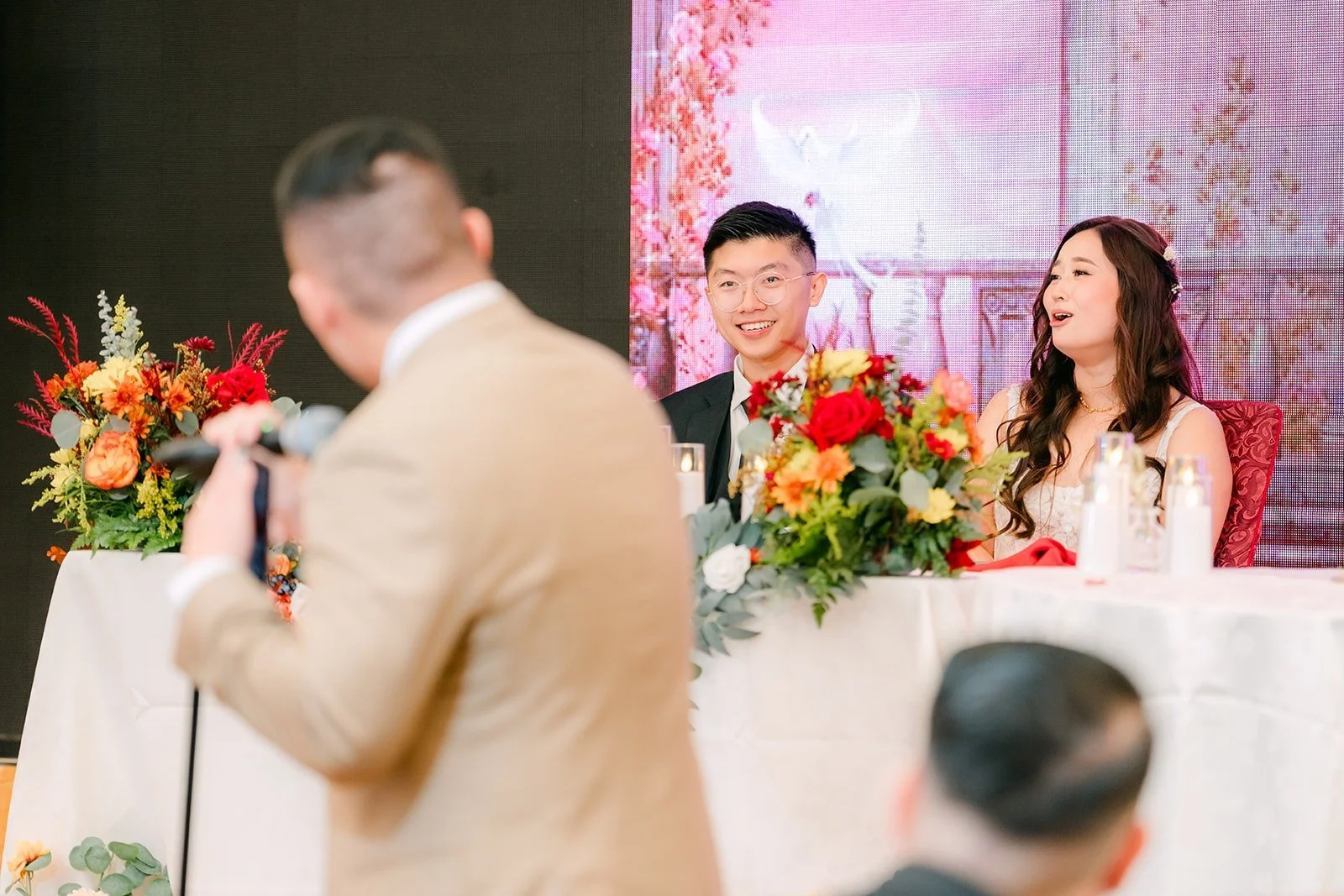 A groomsman speaks to Shayna and Robert at the sweetheart table