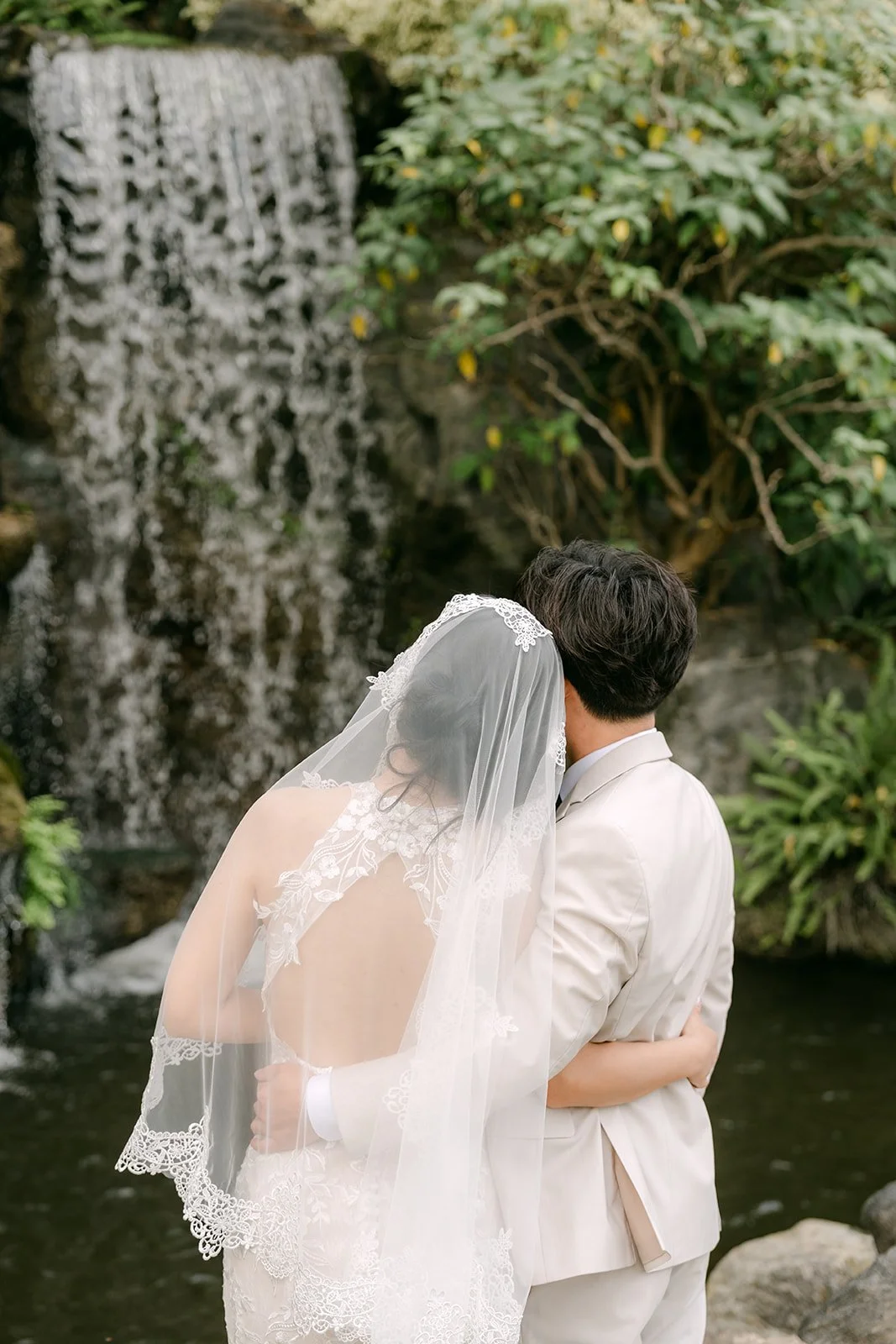 Elaine and Wen at the waterfall from behind, her veil falling.