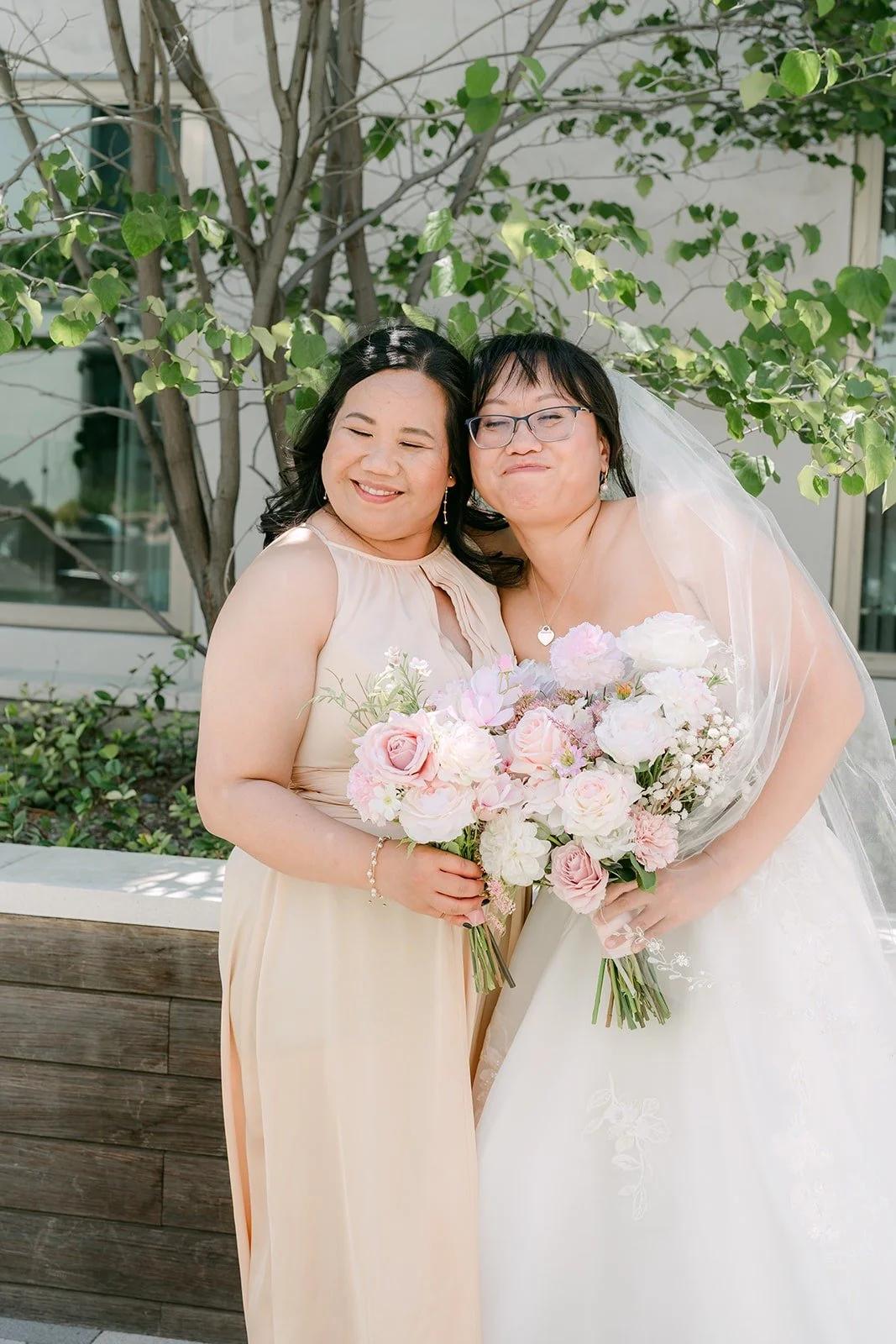 Stella sharing a cheek to cheek moment with a bridesmaid in a champagne gown