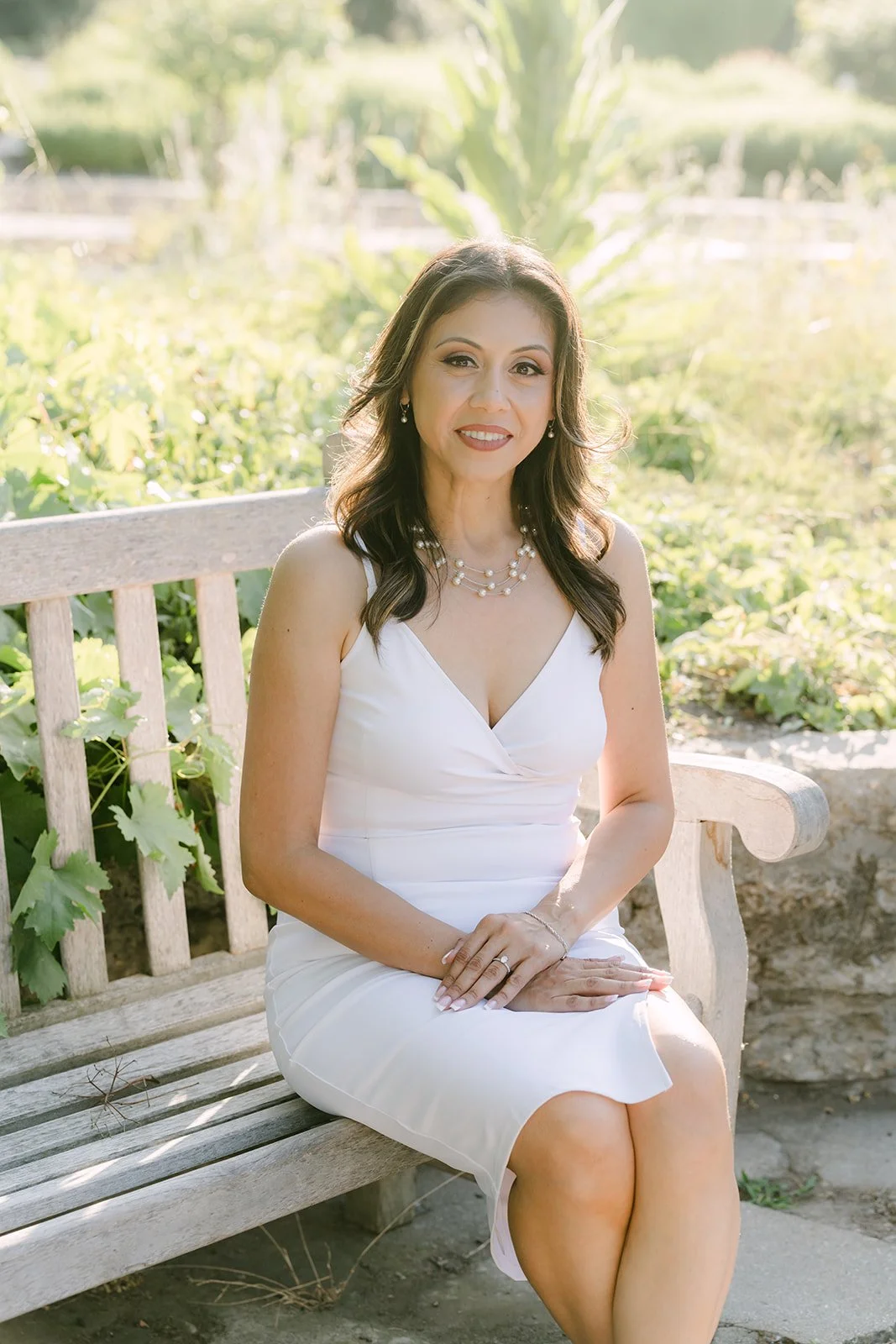 Francesca sits on the gazebo bench in a white dress.