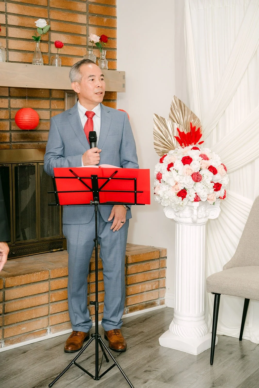The emcee welcomes both families from a red podium at the start of the tea ceremony