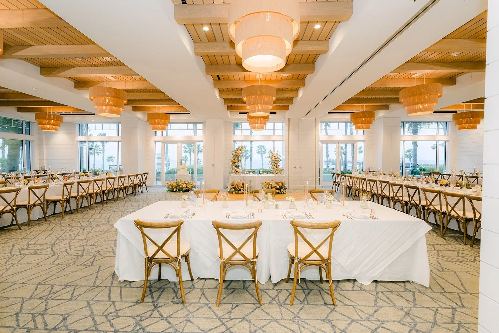 The ballroom at Seabird Resort set for dinner beneath wood beams and rattan chandeliers