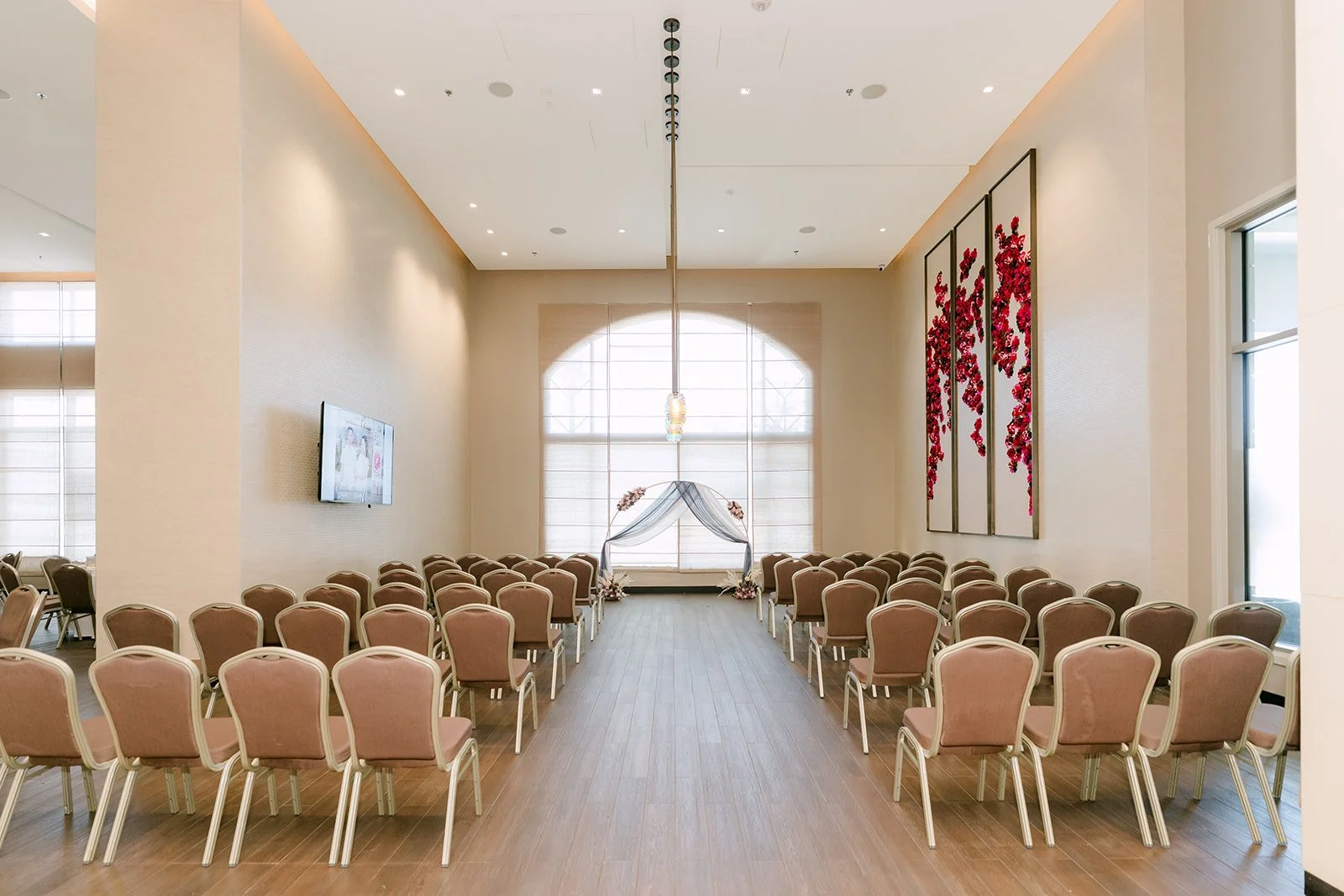 The Opal Room set for the ceremony with arched windows and red florals.