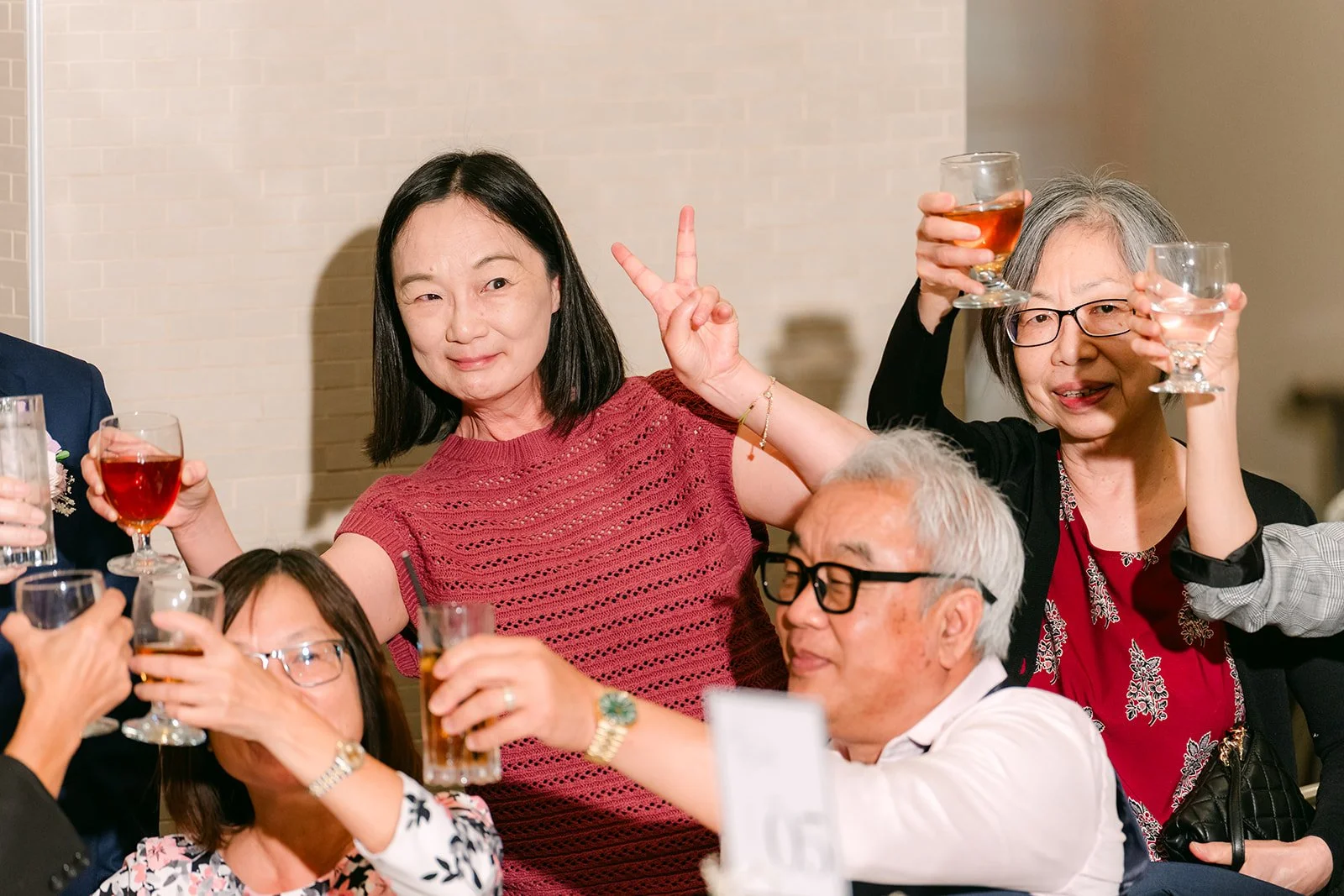Friends toasting and laughing at their table, photographed by One and Only Production.