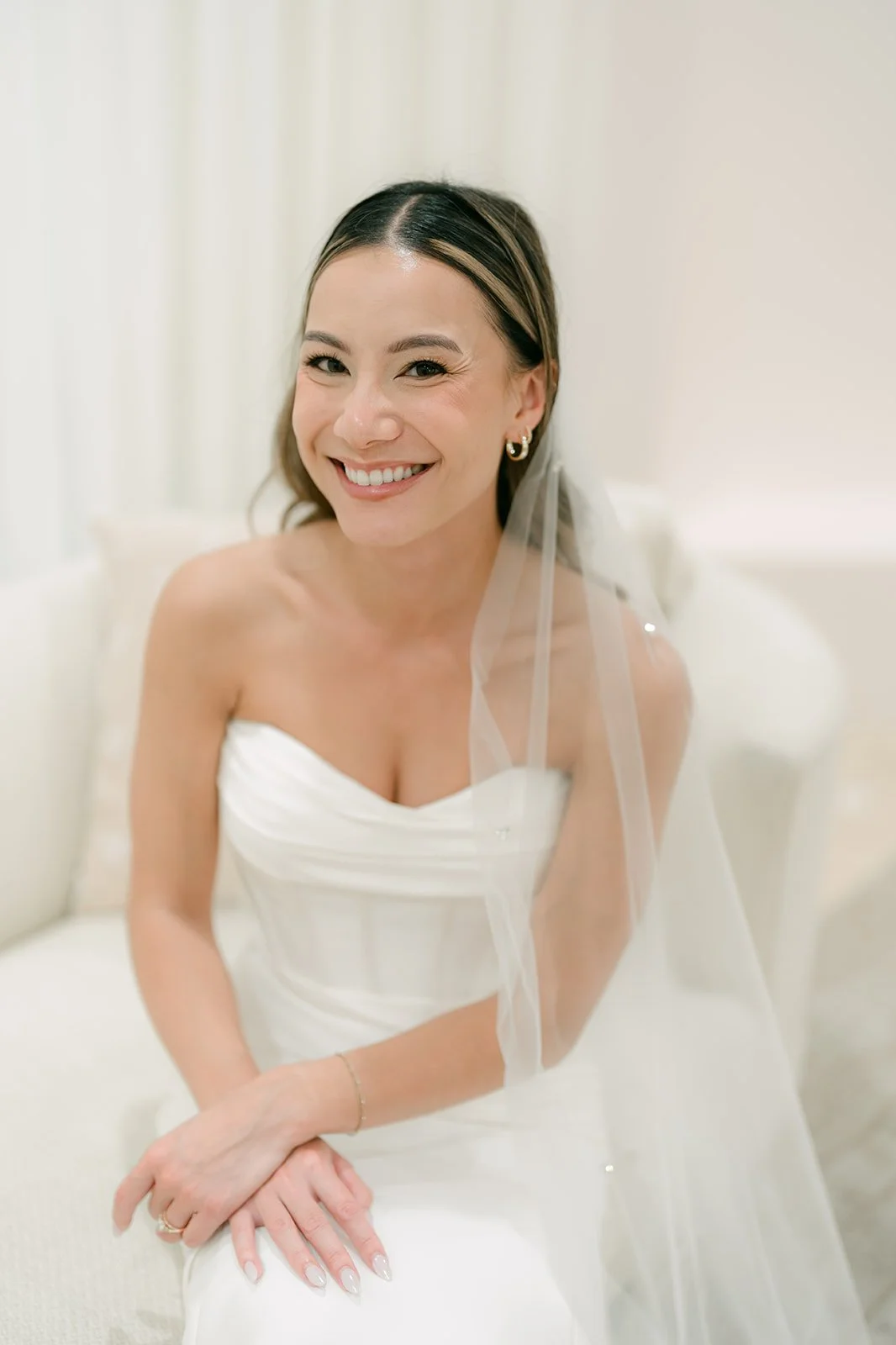Kieu smiling in her strapless gown and veil in soft window light