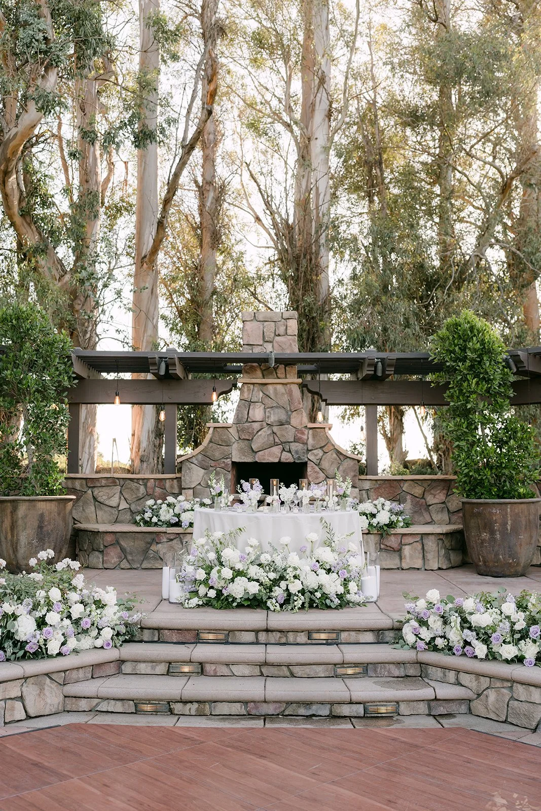 Sweetheart table in front of the stone fireplace with white florals
