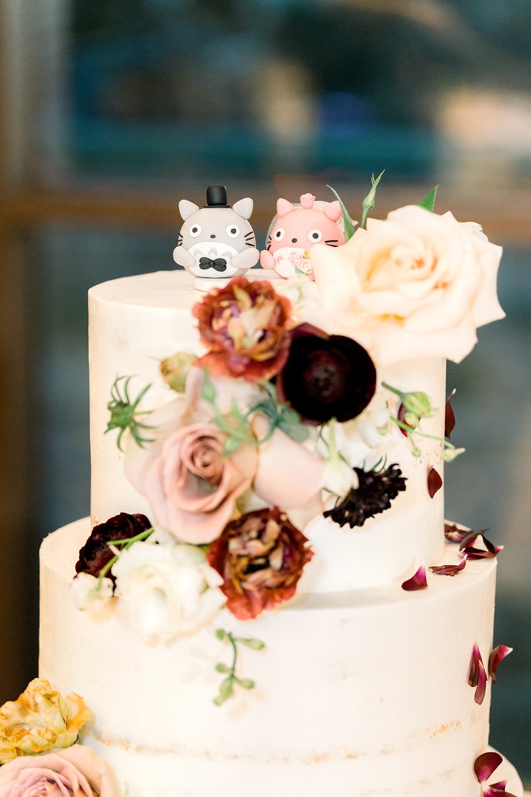 The cake with Totoro toppers and burgundy and blush sugar flowers