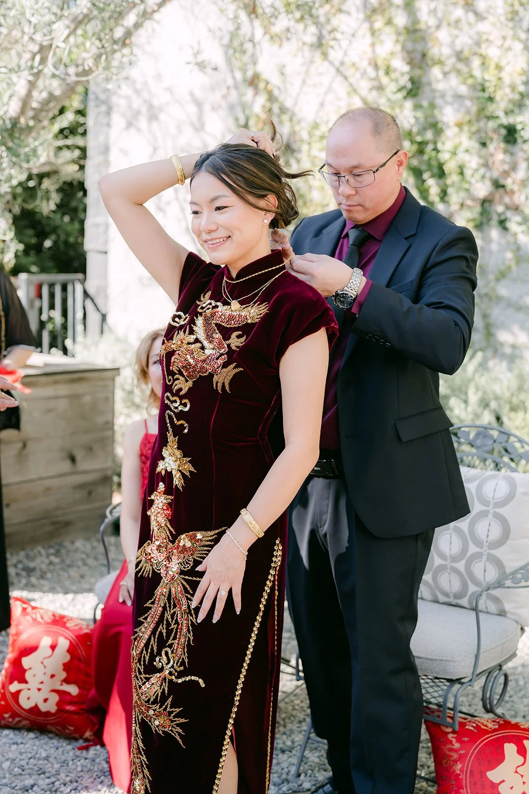 Jadee in her burgundy qipao with a family member