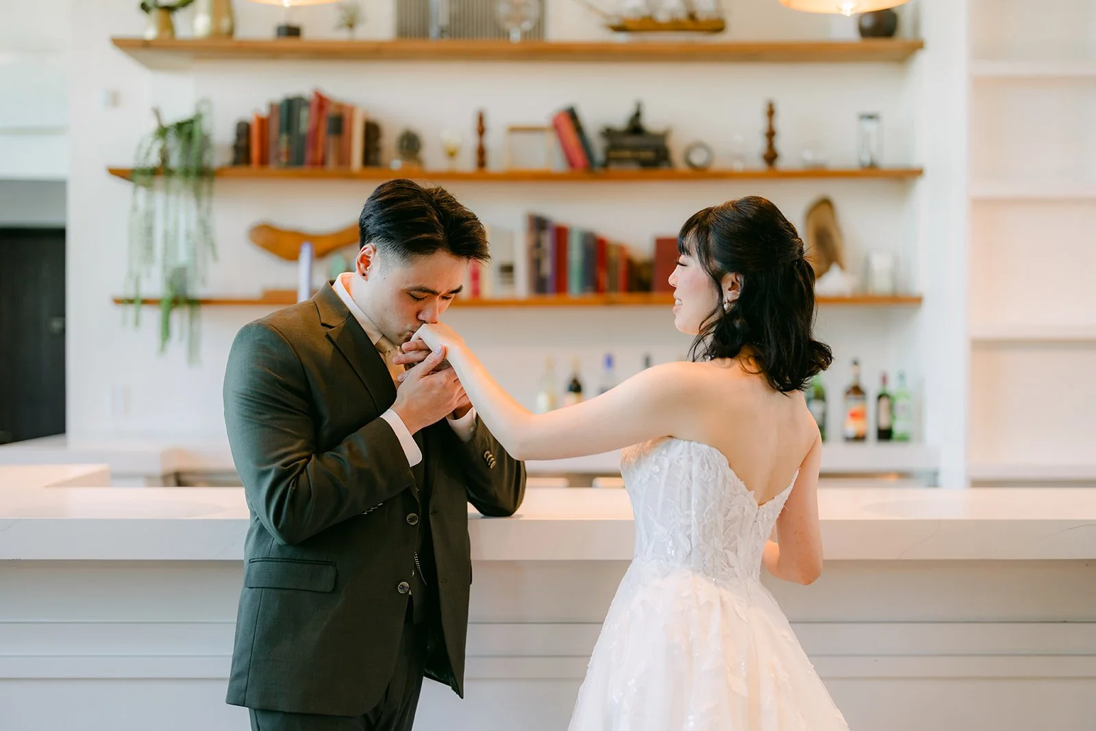 Alex kissing Vivian's hand in front of the shelves