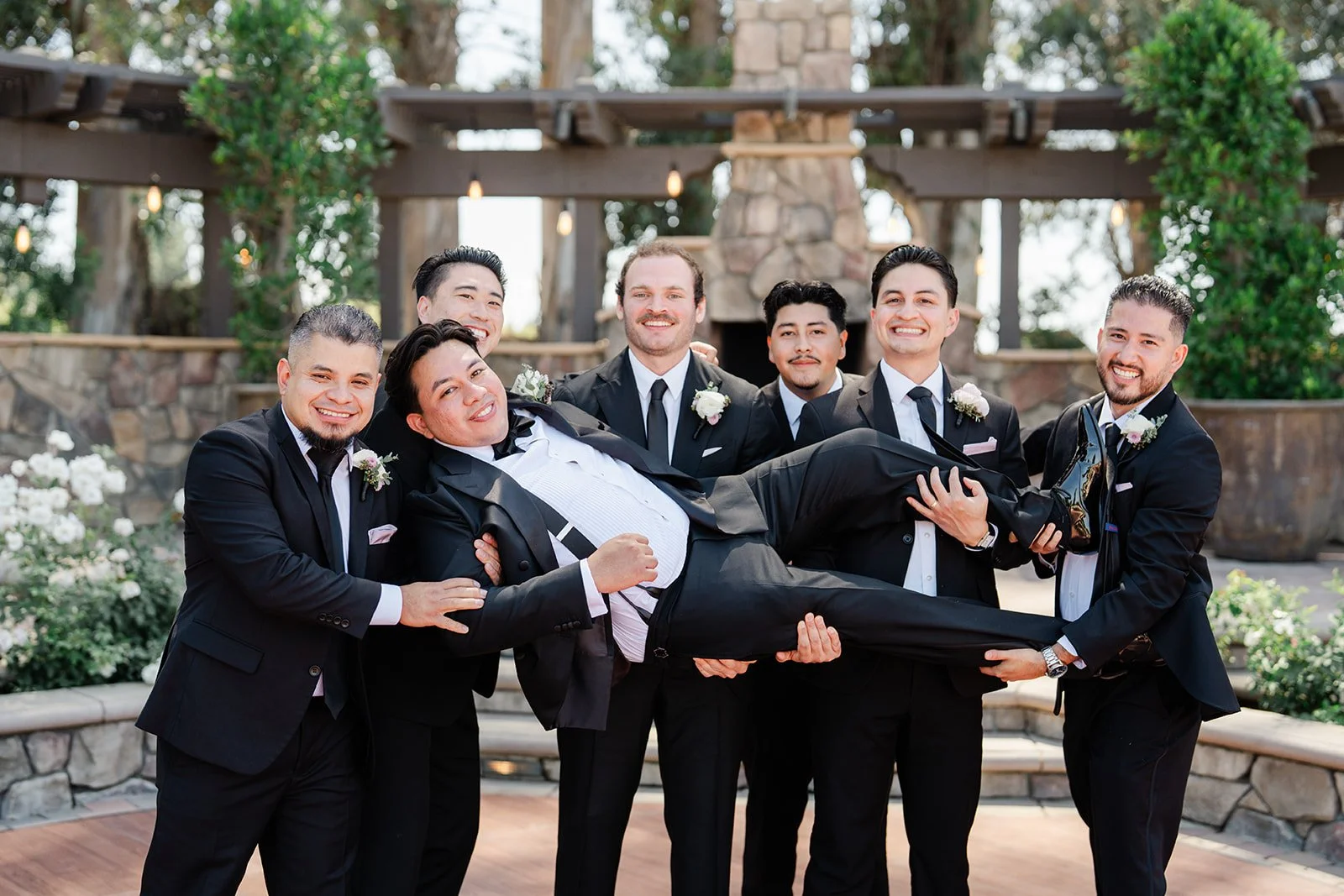 Groomsmen lifting the groom sideways