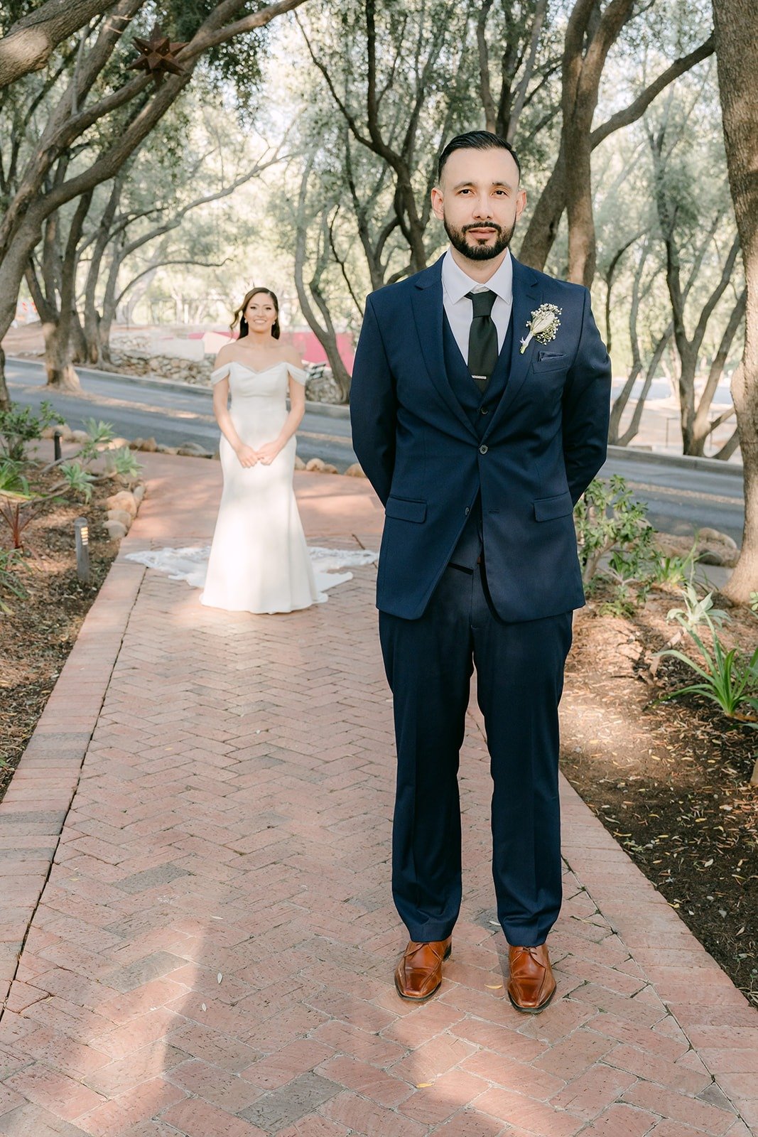 Danny waiting with his back turned as Mariana walks up the brick path