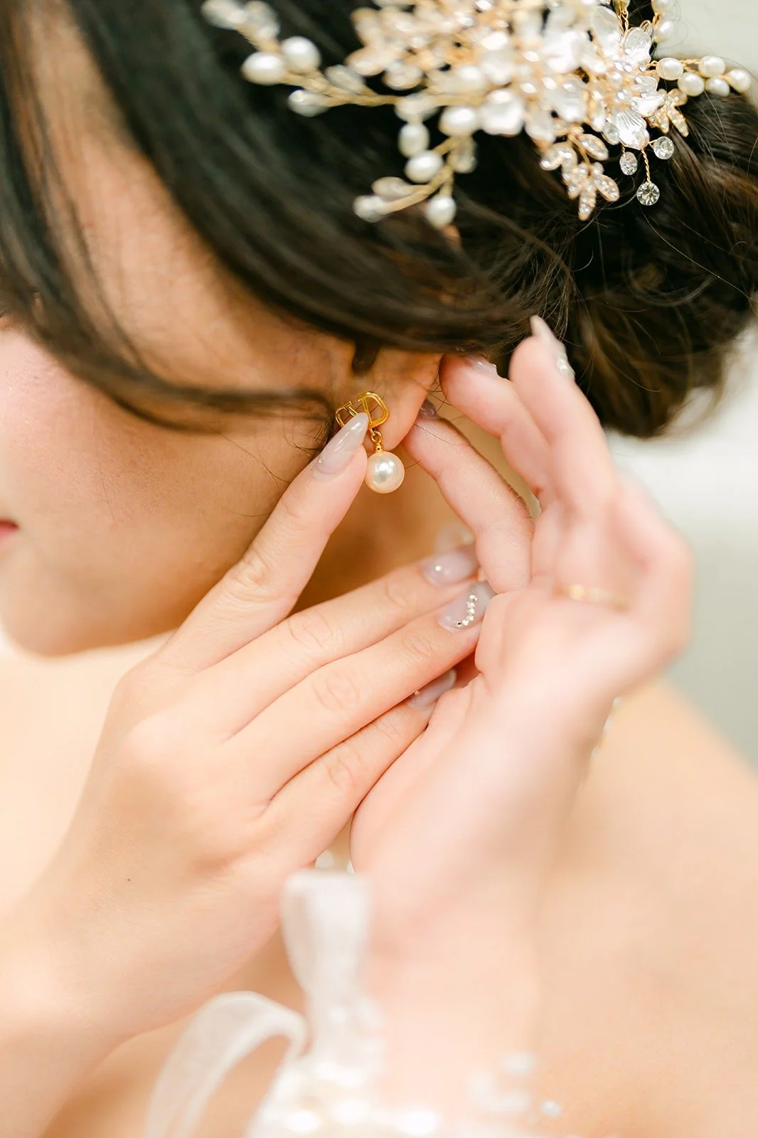 Ivy putting on her earrings under a jeweled hairpiece