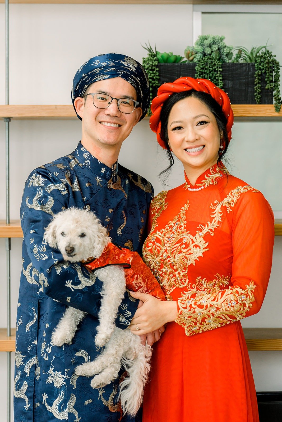 Cindy and Alex in traditional attire holding the white dog