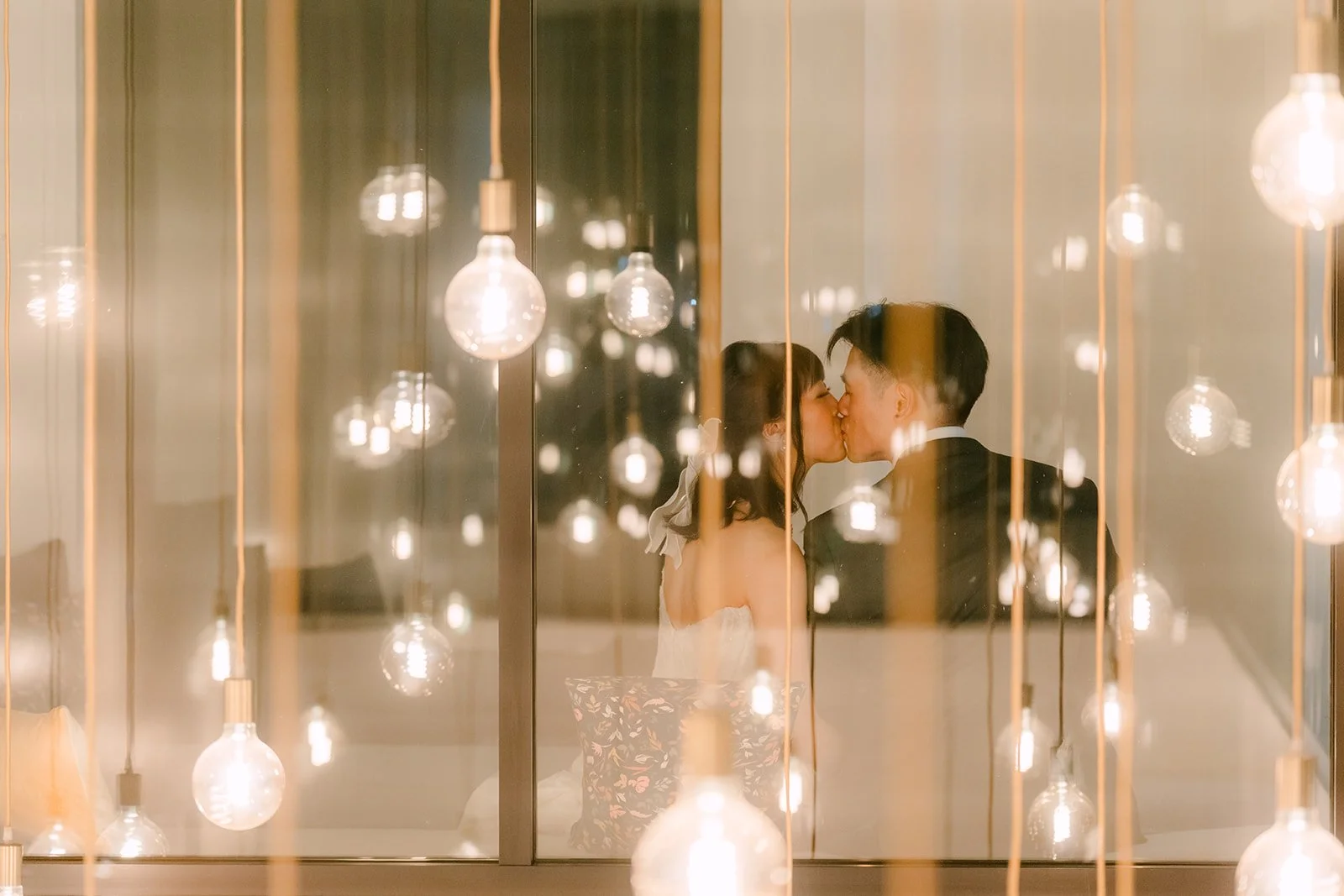 Night portrait of the couple through glowing hanging lights at The Colony House