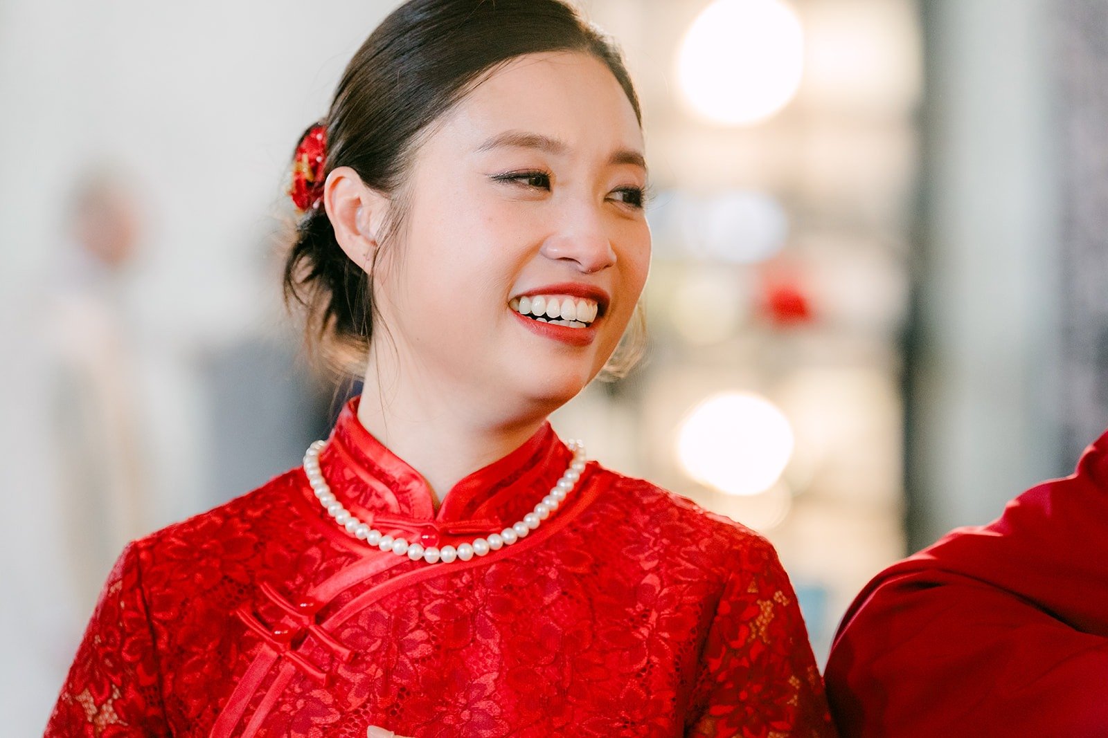 Elisa laughs in her red qipao and pearl necklace