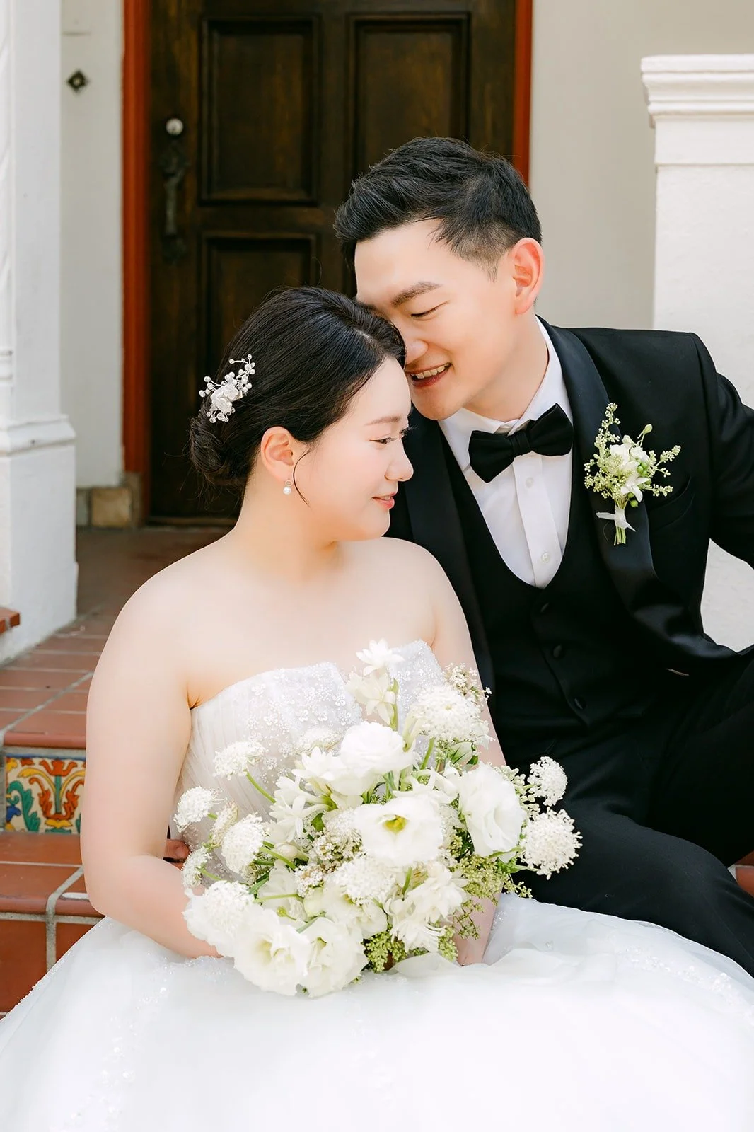 Sam nuzzling Amy as she holds her bouquet