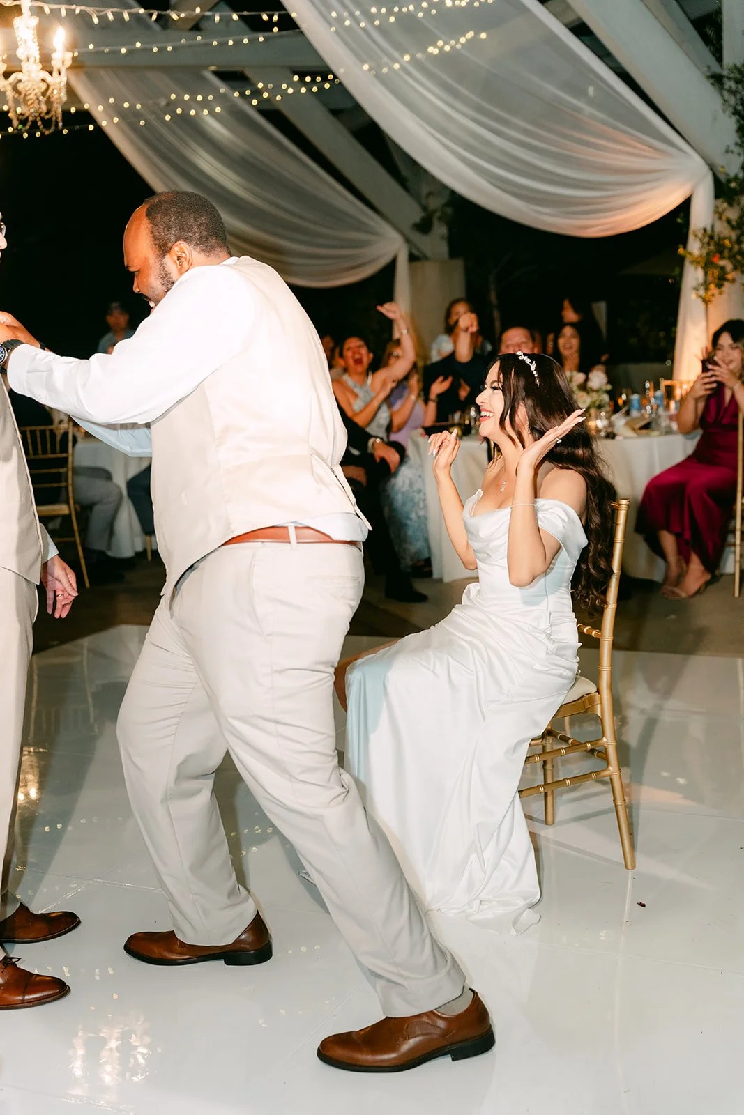 Kevin dancing his way over for the garter removal as guests laugh.