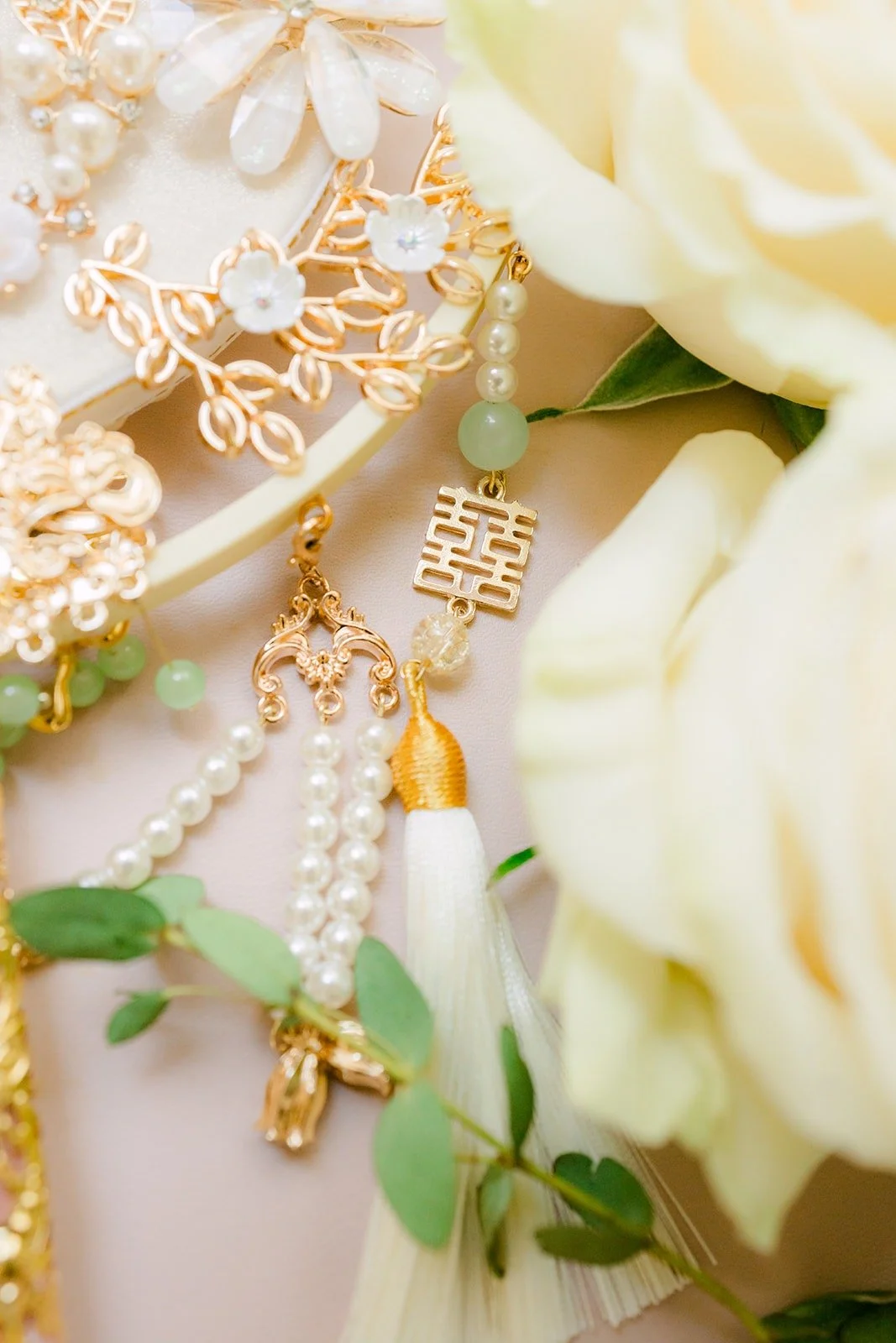 Close up of Tin's gold and pearl jewelry among cream roses, photographed by One and Only Production