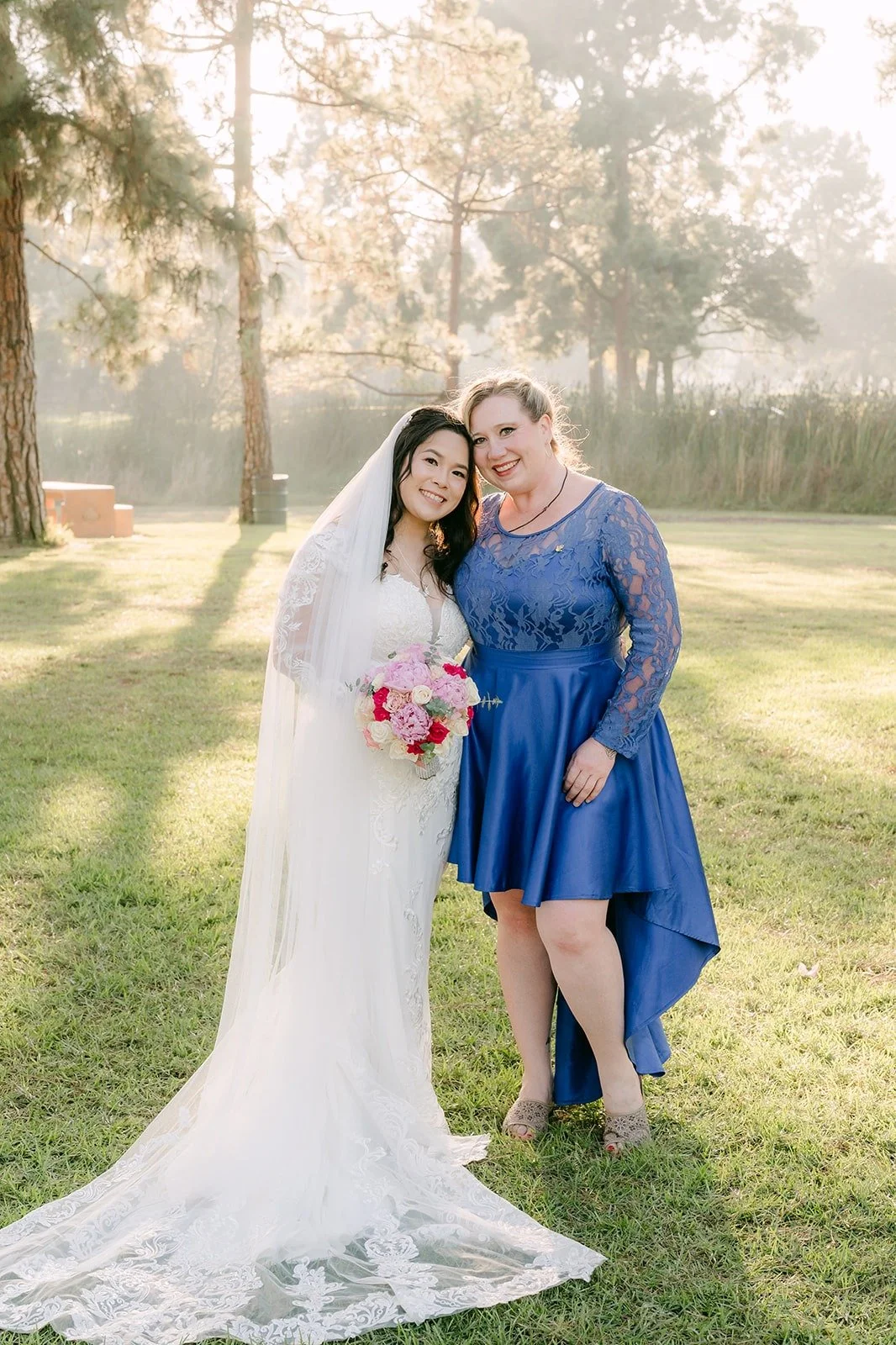 Amy with a guest in a blue lace dress on the lawn