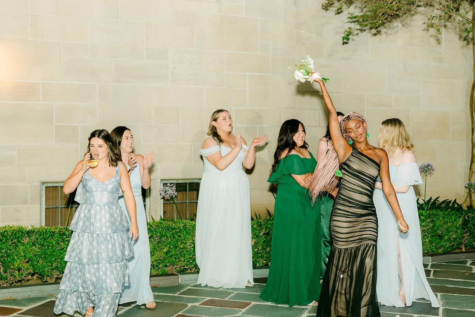 A guest catching Brianna's bouquet as everyone cheers, photographed by One and Only Production