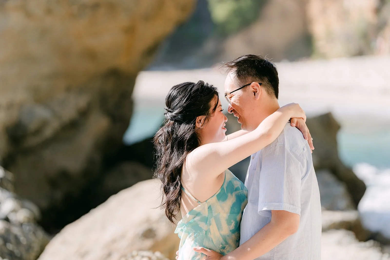 Lawrence hugging Constance from behind against the sandstone.