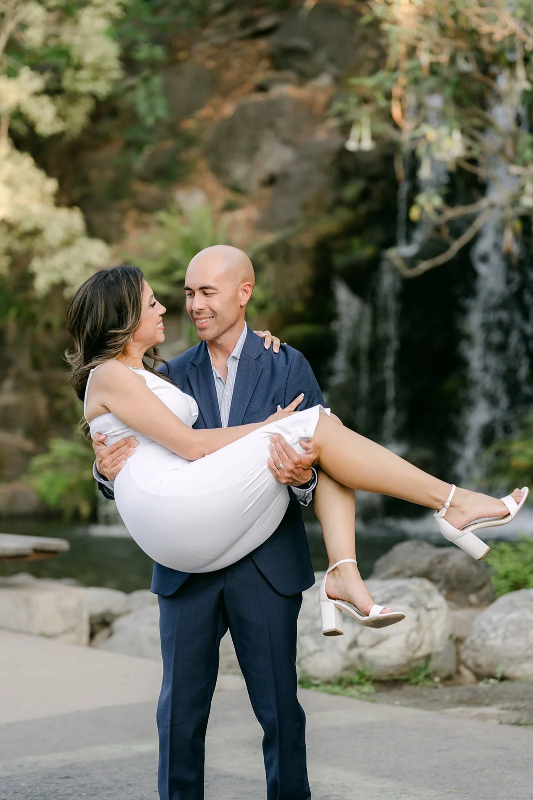 Daniel lifts Francesca as she kicks up her heels by the waterfall.