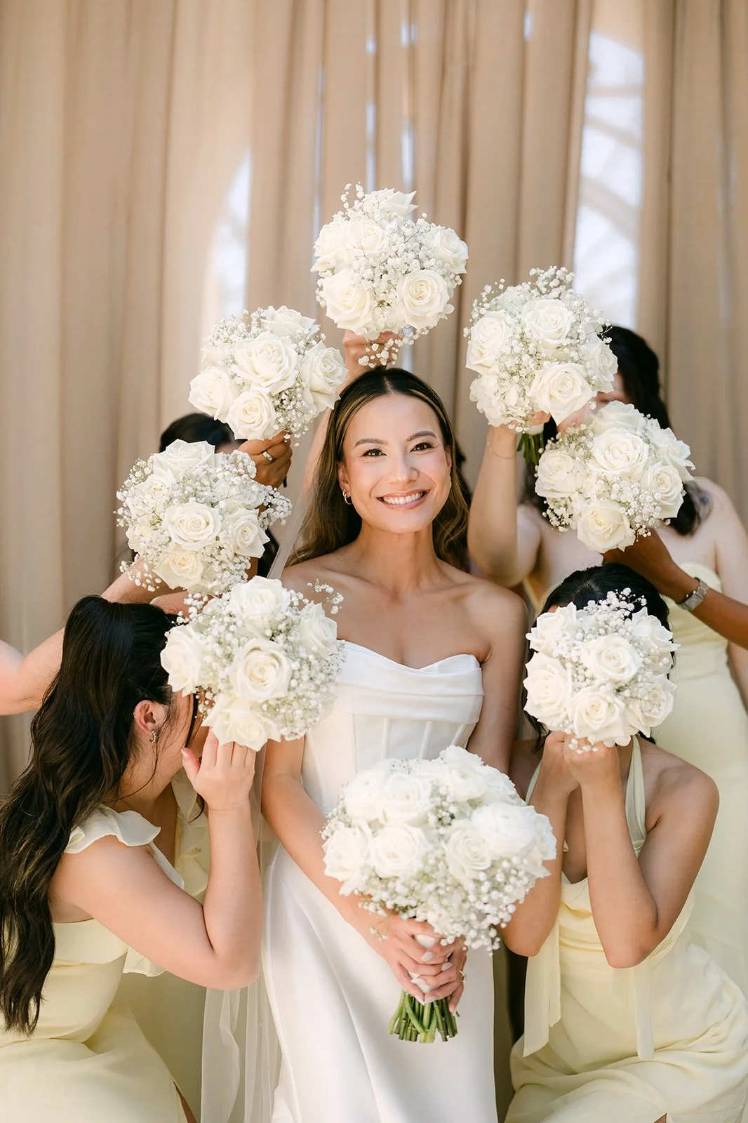 Bridesmaids in butter yellow framing the bride with white rose bouquets