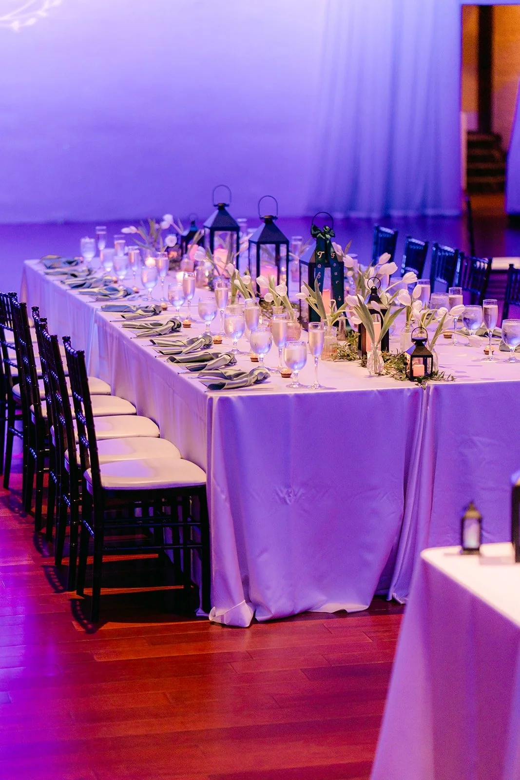 Long reception tables with white linens and candles in the ballroom at Padua Hills Theatre