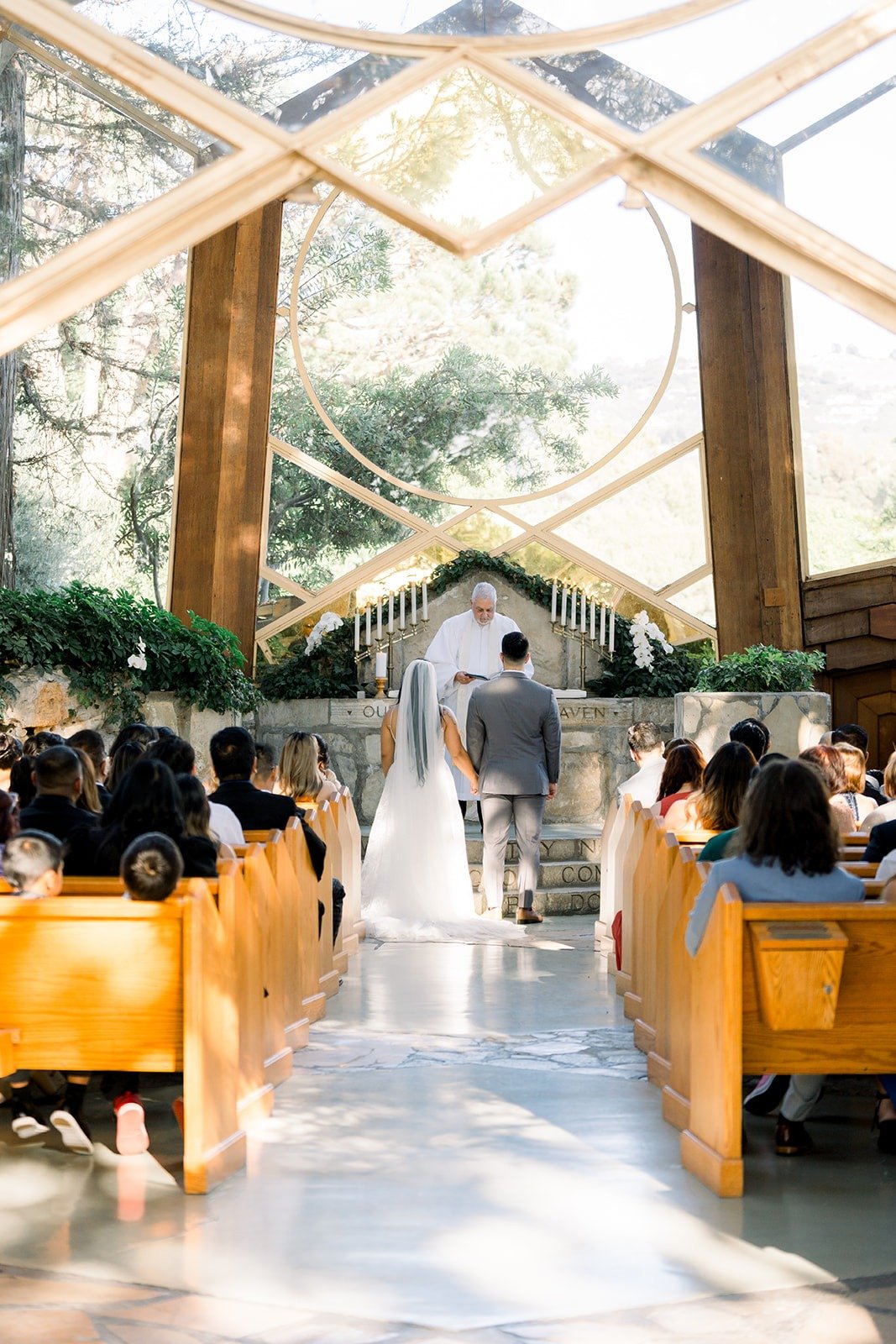 Betsy walks down the aisle under the glass and timber roof of Wayfarers Chapel