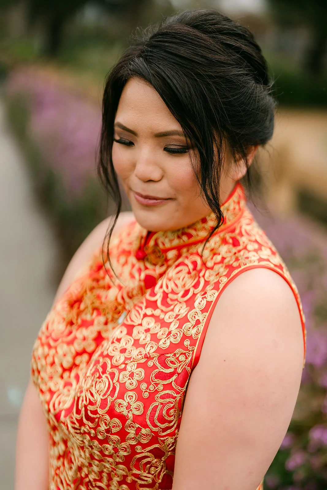 A bride in a gold sequined qipao looking down in soft garden light.