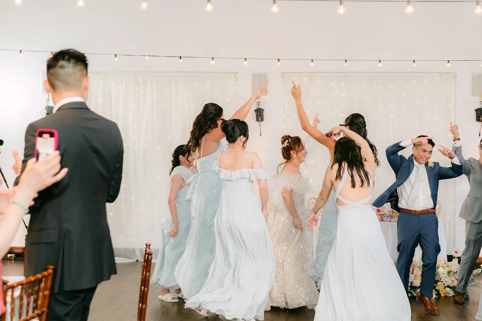 The wedding party dancing in as guests clap along