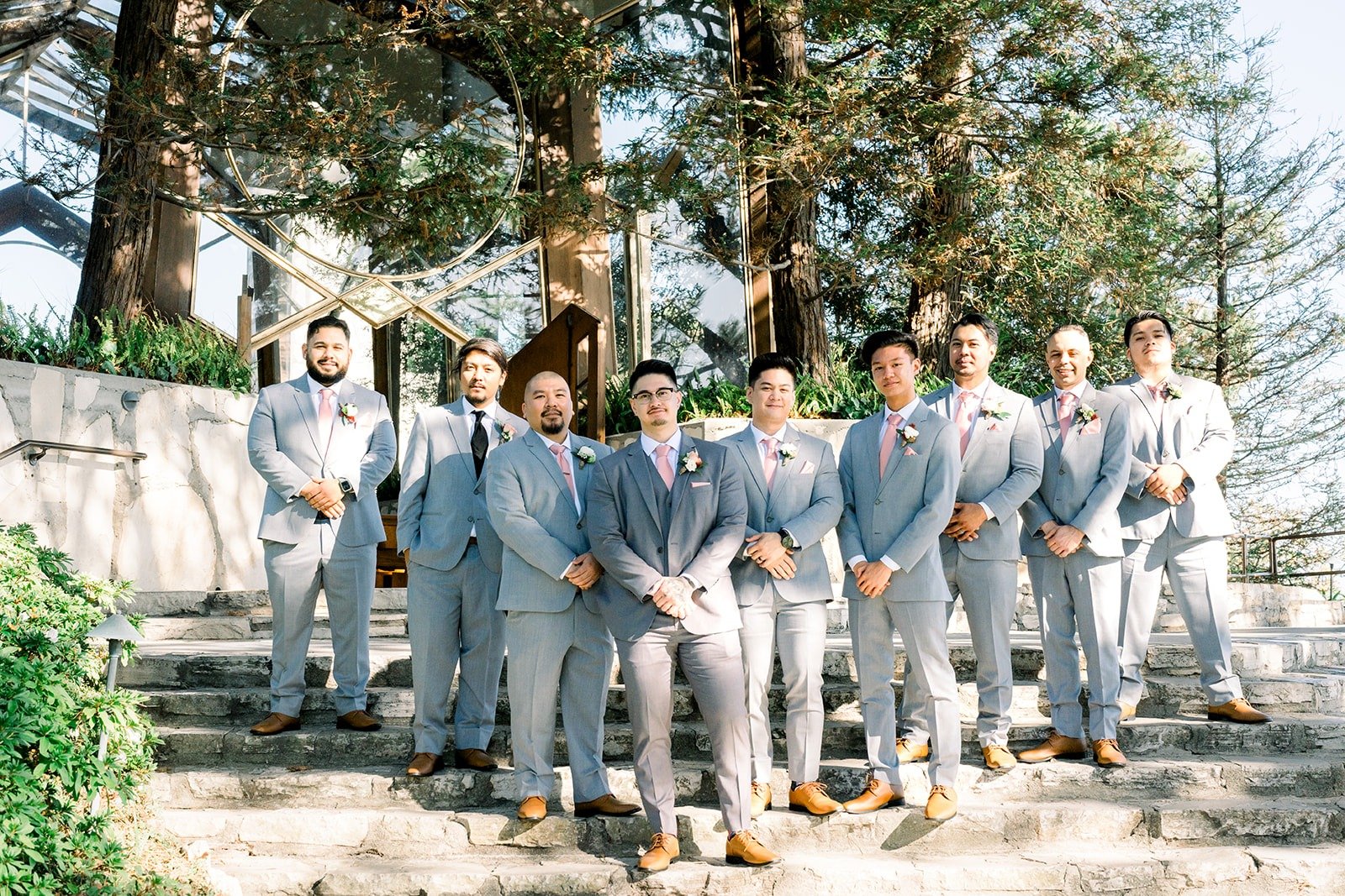 Mikey and his groomsmen in grey suits by a stone wall