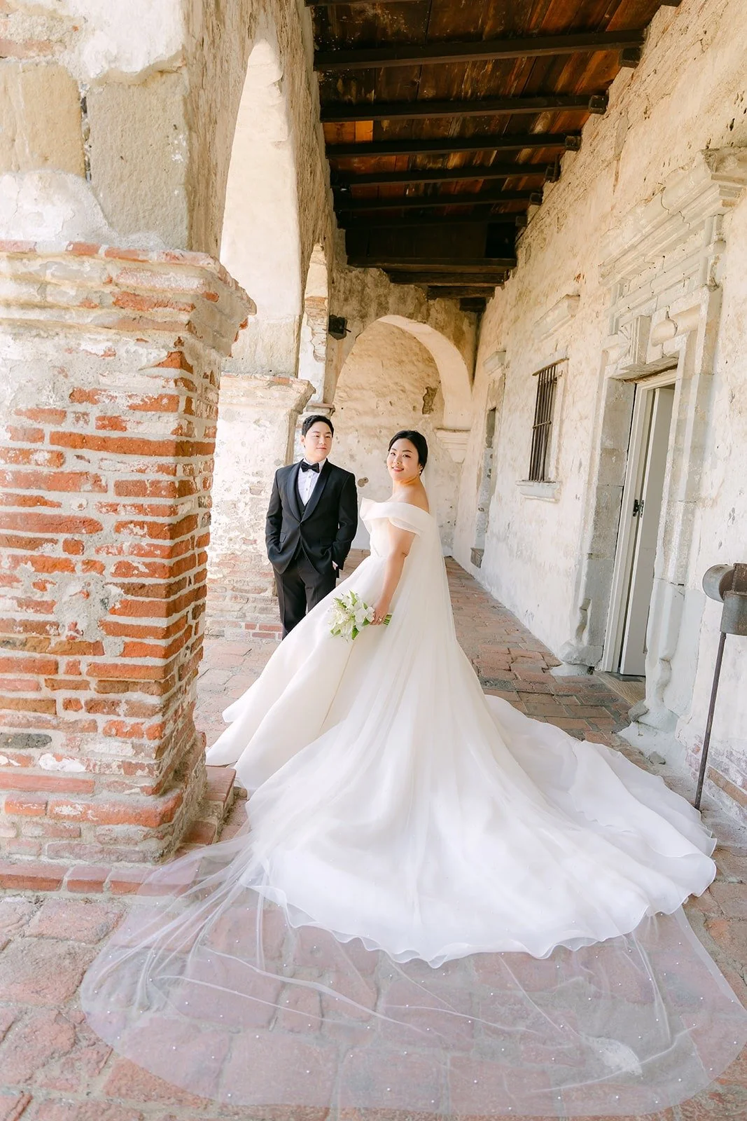 Chorok and Min Soo in a long covered arcade at Mission San Juan Capistrano