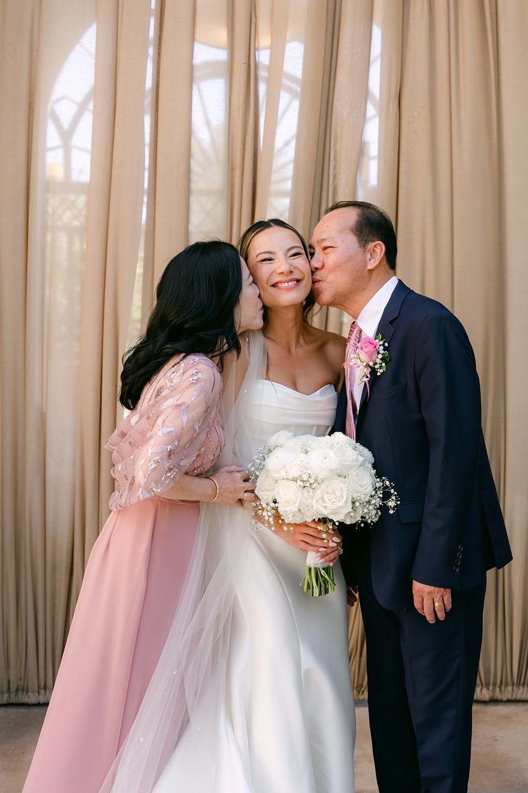 Bride's parents kissing her cheeks before the ceremony
