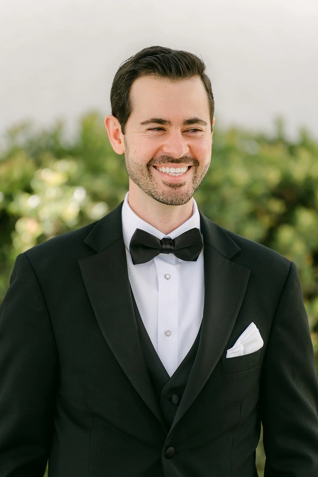 A smiling portrait of Kevin in his black bow tie and white pocket square