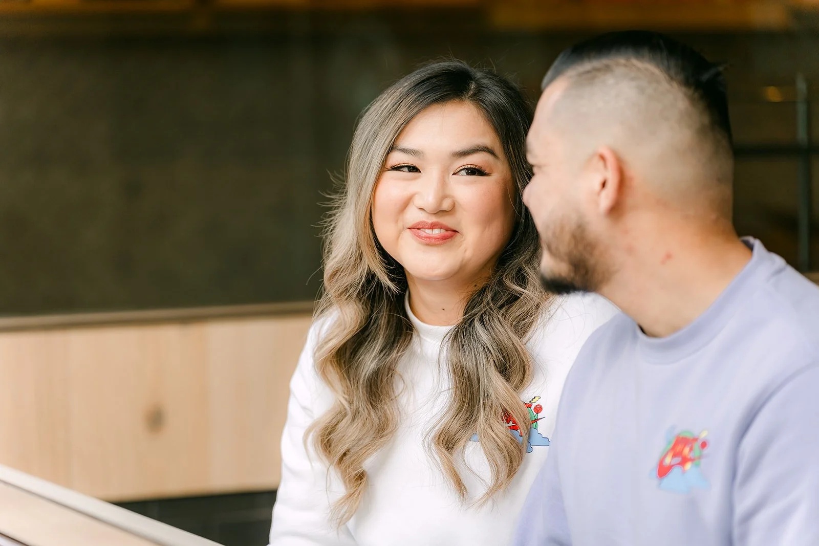 Linh smiles at the camera while Ankush looks at her.