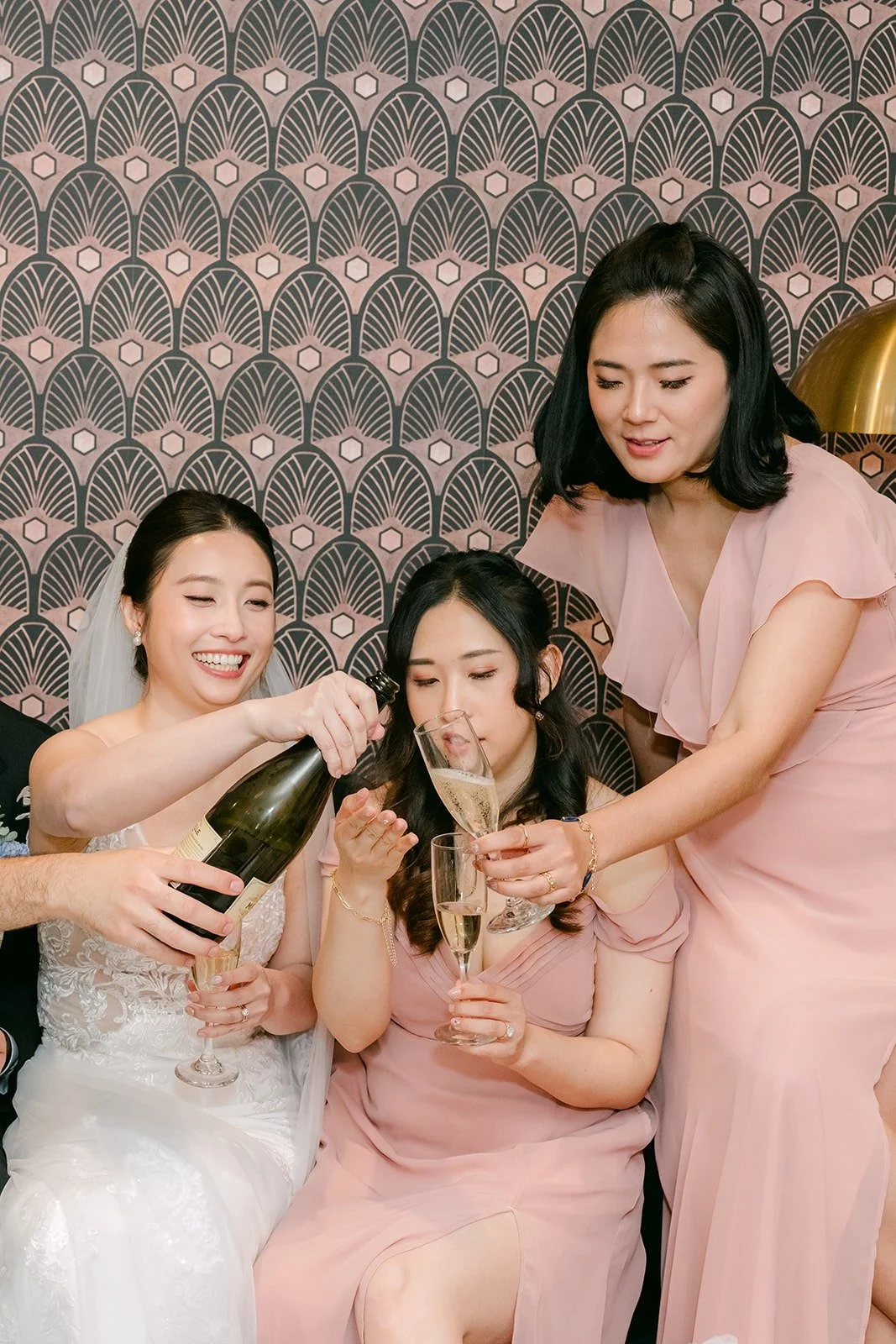 Elisa and her bridesmaids pop a bottle of champagne, photographed by One and Only Production