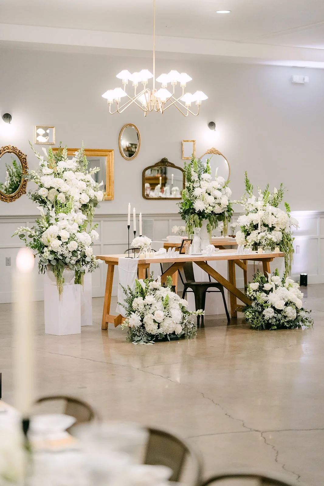 Sweetheart table with a gold mirror and white florals in the reception room at The Harper
