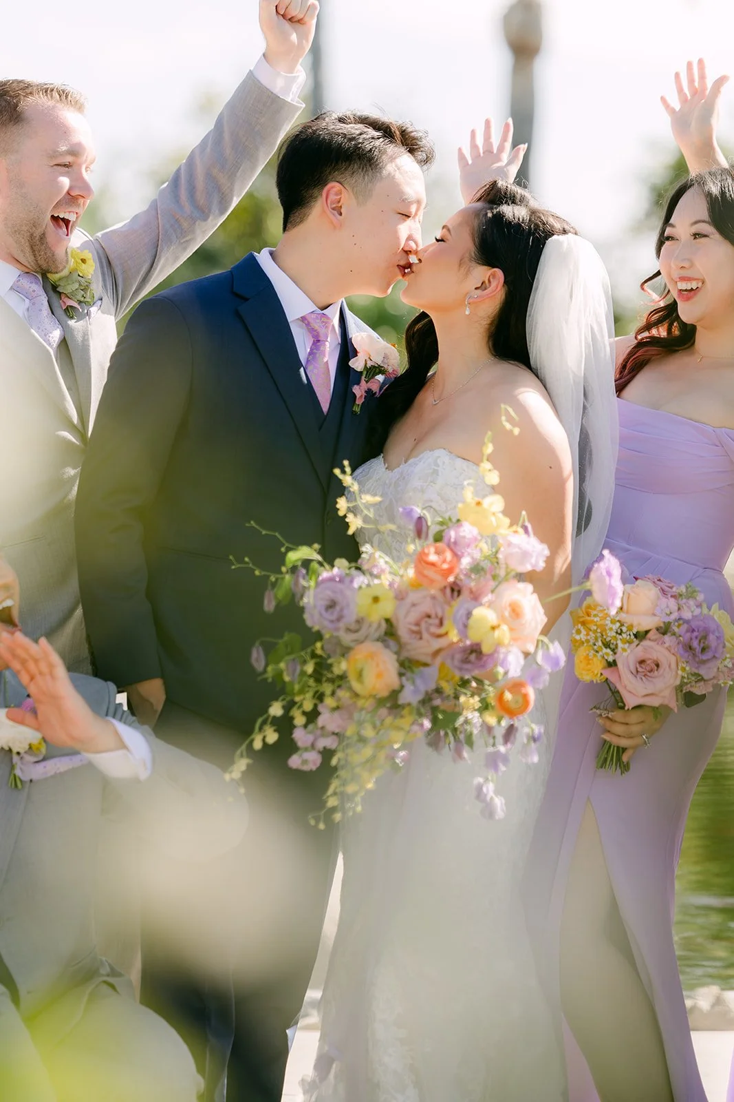 Vannie and Elijah kissing as the wedding party cheers.