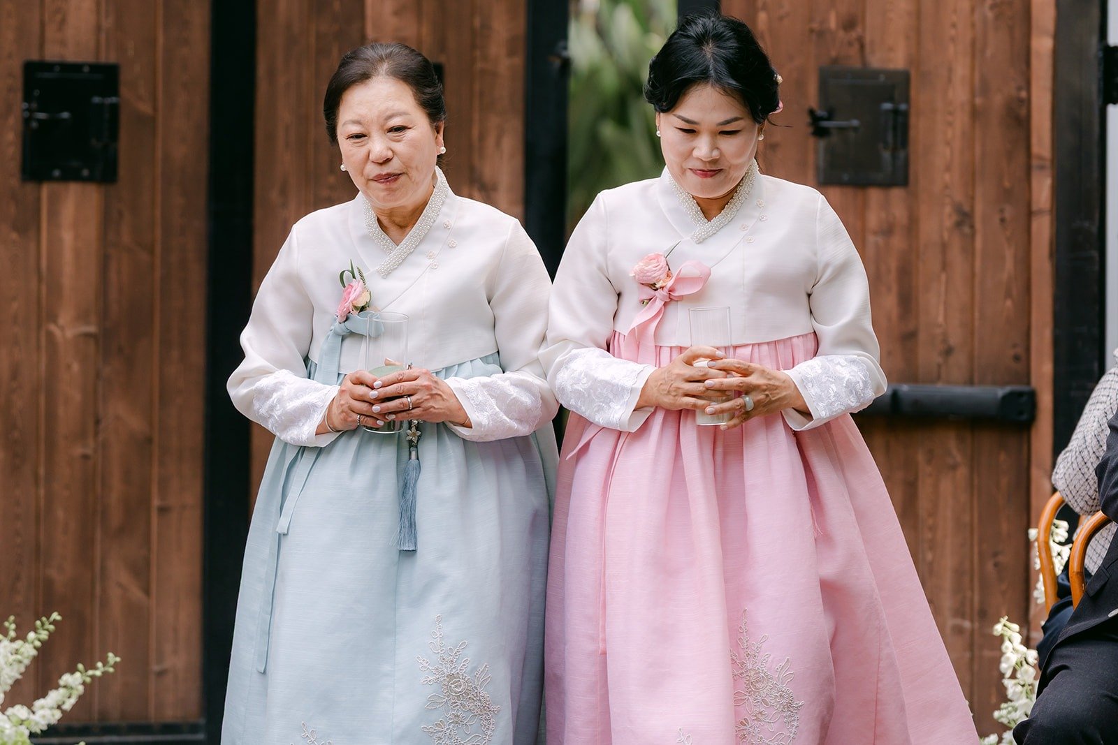 Two family members in pink and blue hanbok standing together before the ceremony