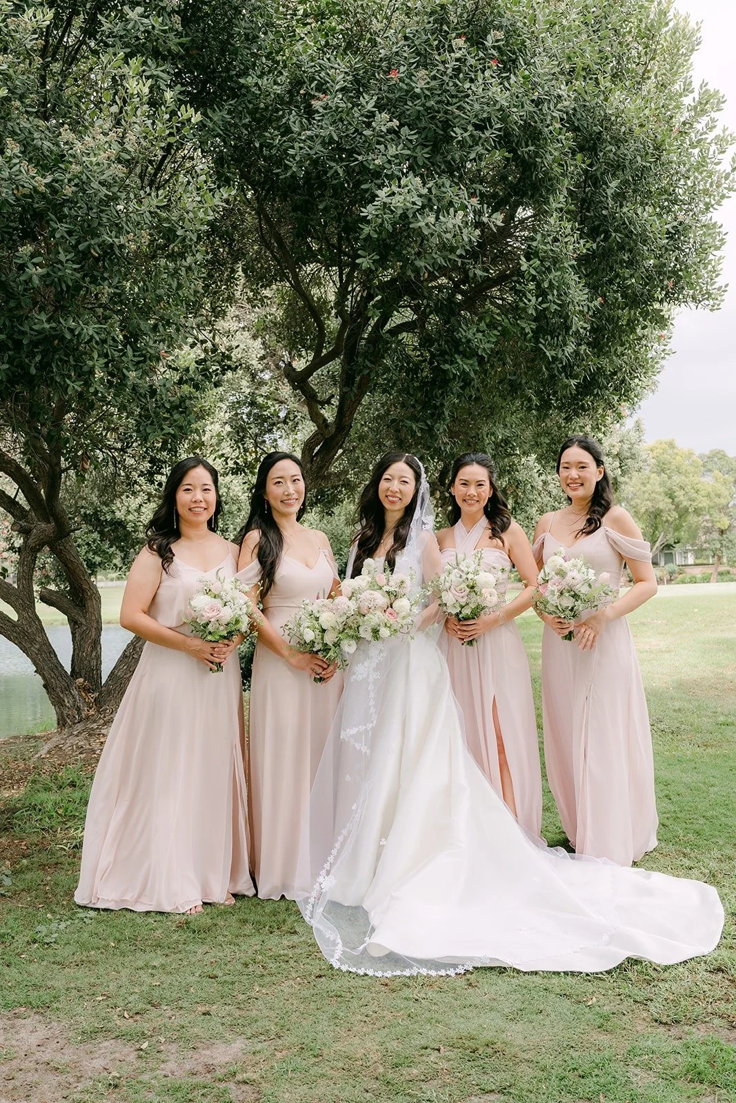 Kristine and her bridesmaids lined up under the trees