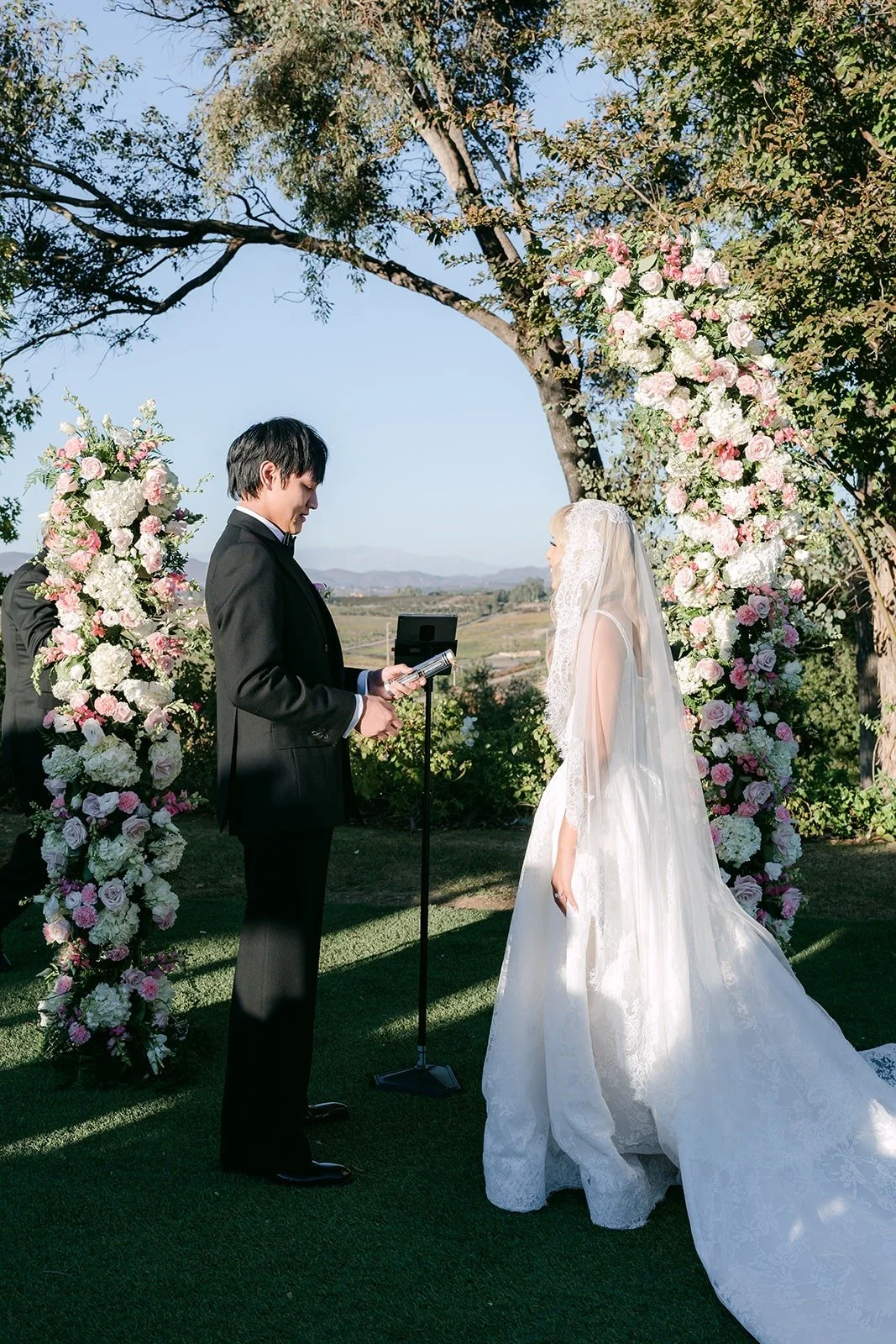Konitha and Job at the altar framed by blush florals, photographed by One and Only Production