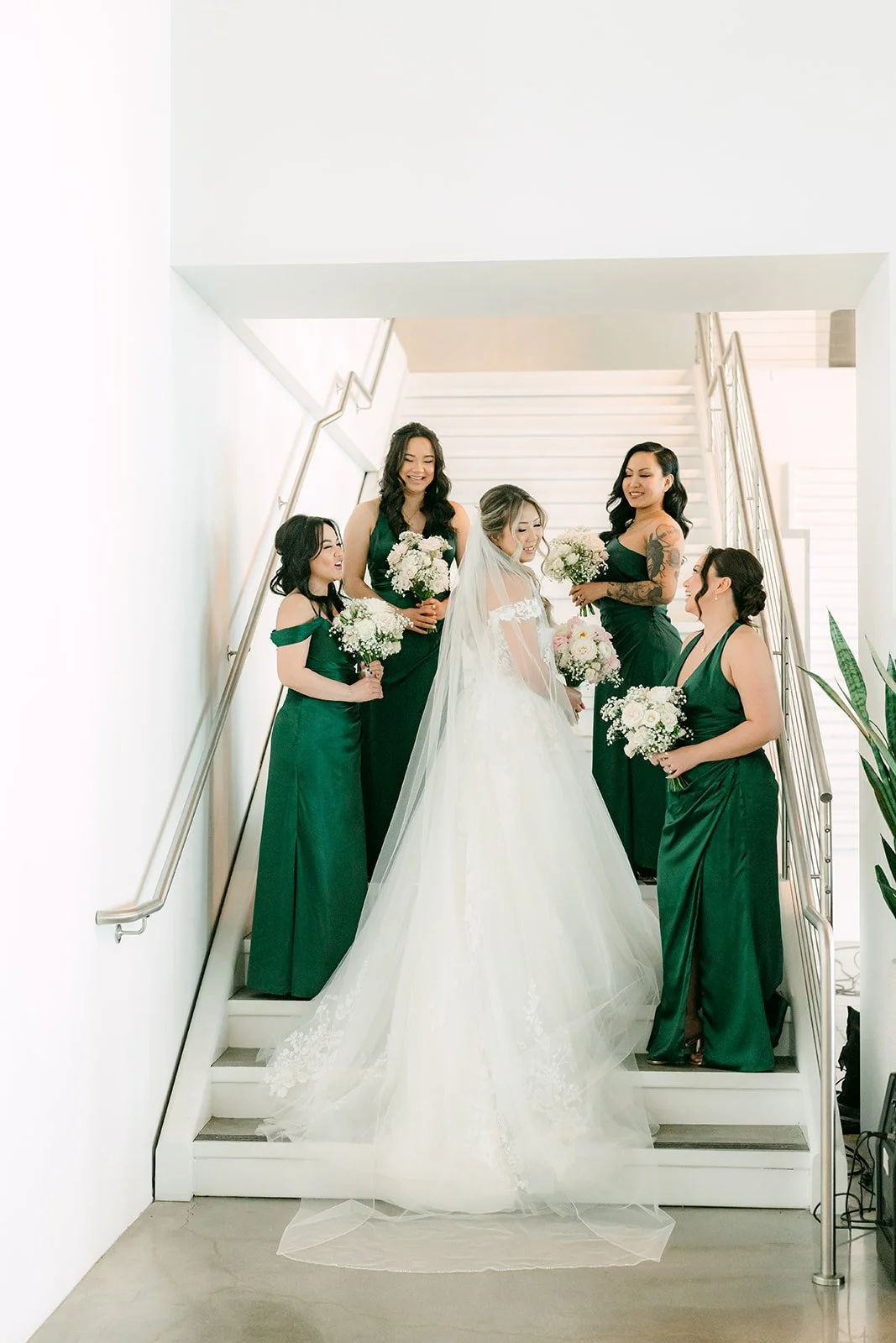 Bride and bridesmaids in emerald dresses on the white staircase