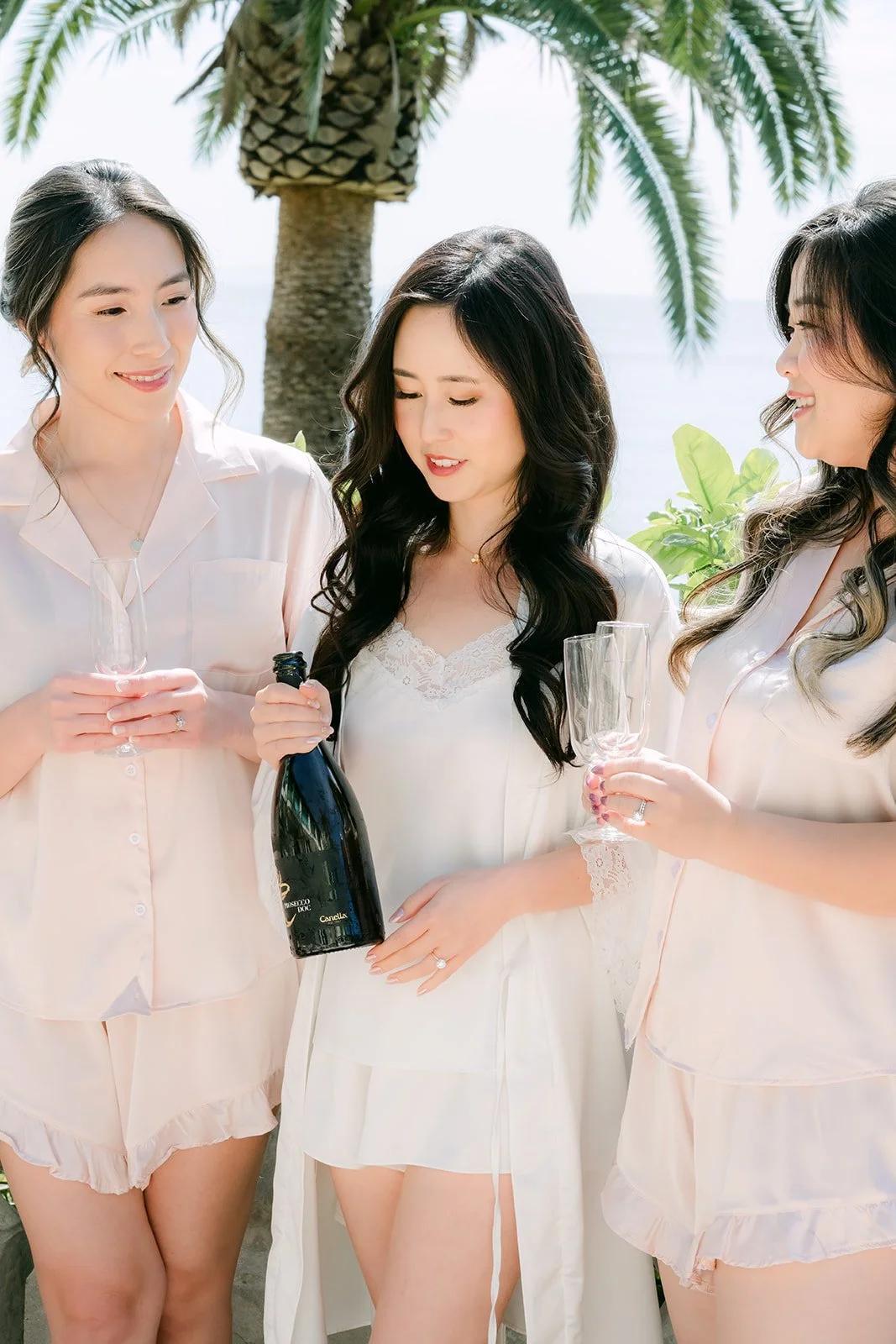 Bride and bridesmaids laughing over champagne while getting ready
